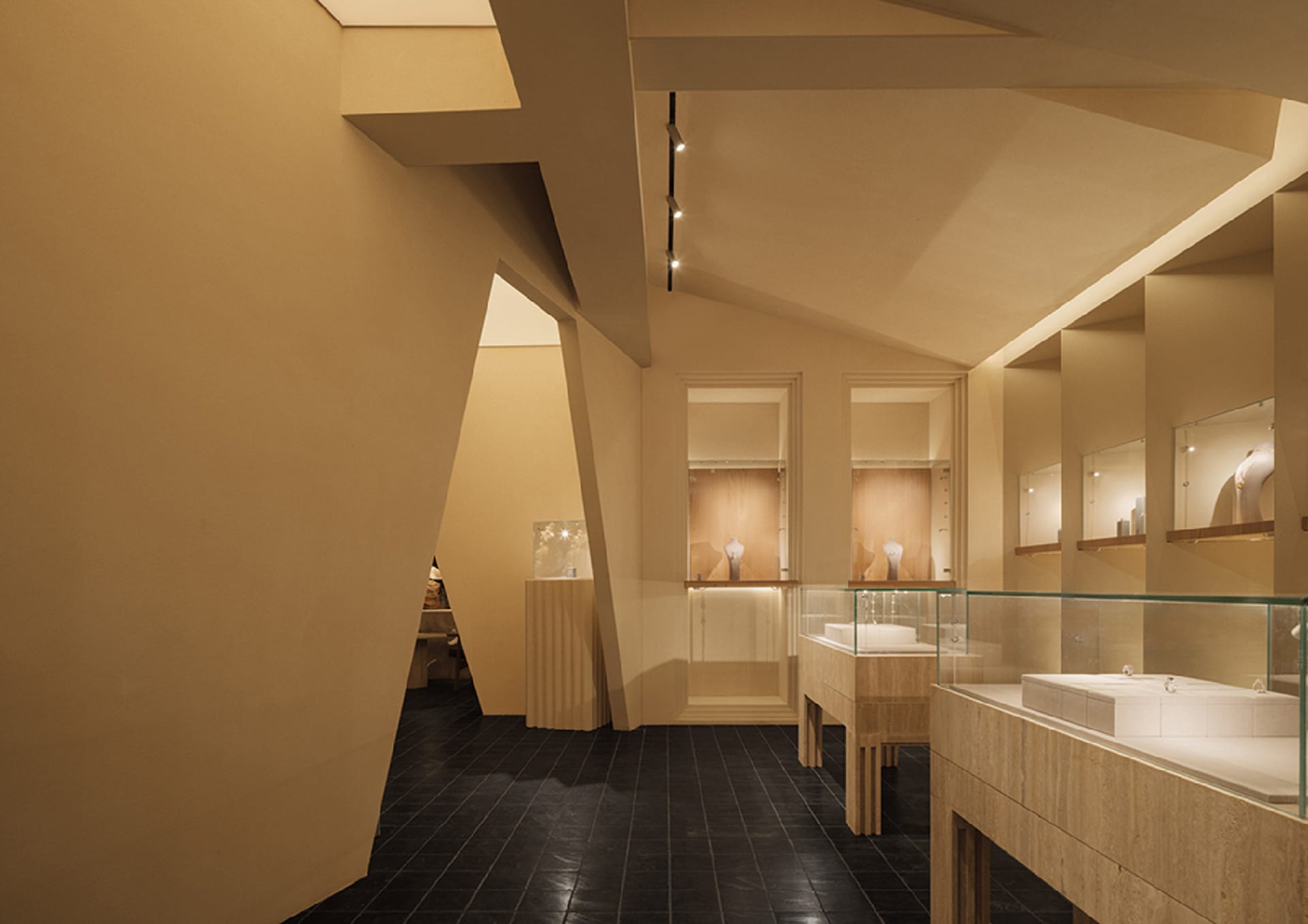 Interior view of a minimalist retail jewelry store featuring a sandstone counter and display cases.