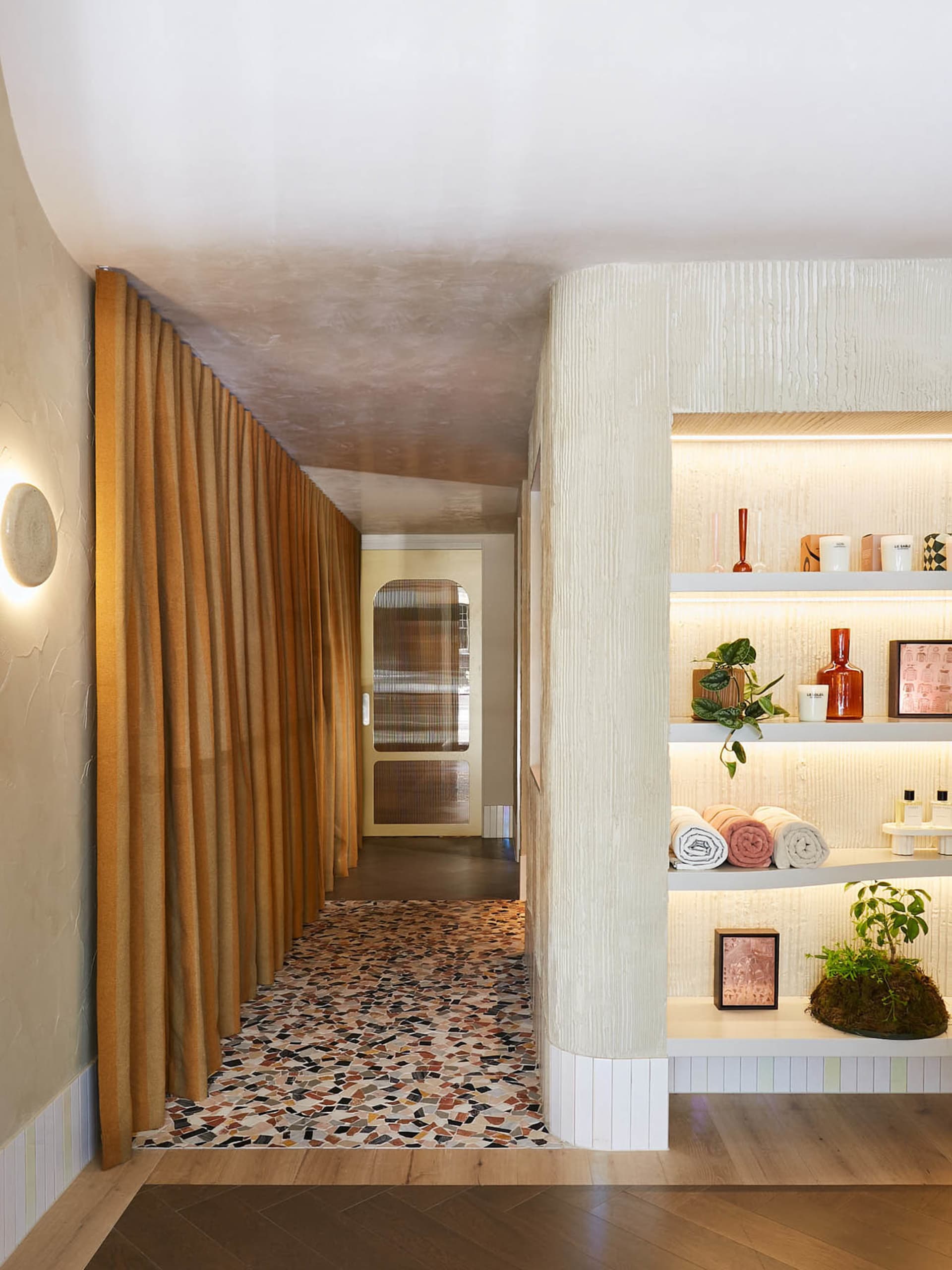 A spa interior with a faux marble texture wall and shelves displaying spa products.