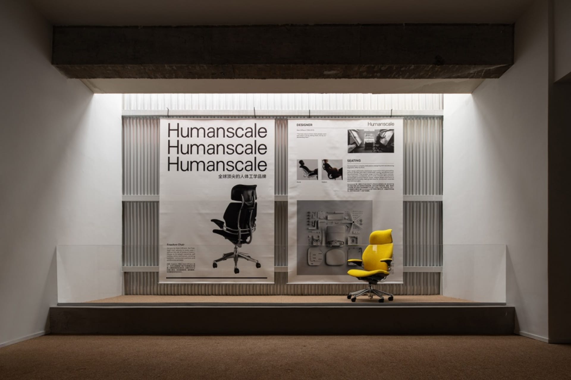 Humanscale 產品展示,黃色辦公椅置於階梯平台上,後方有資訊海報。