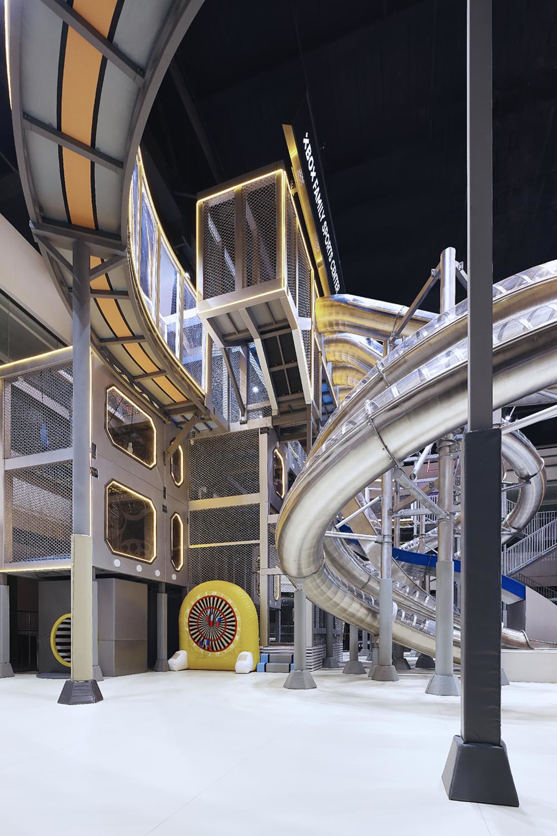 Modern, industrial-style amusement park with metal slides and glass railings