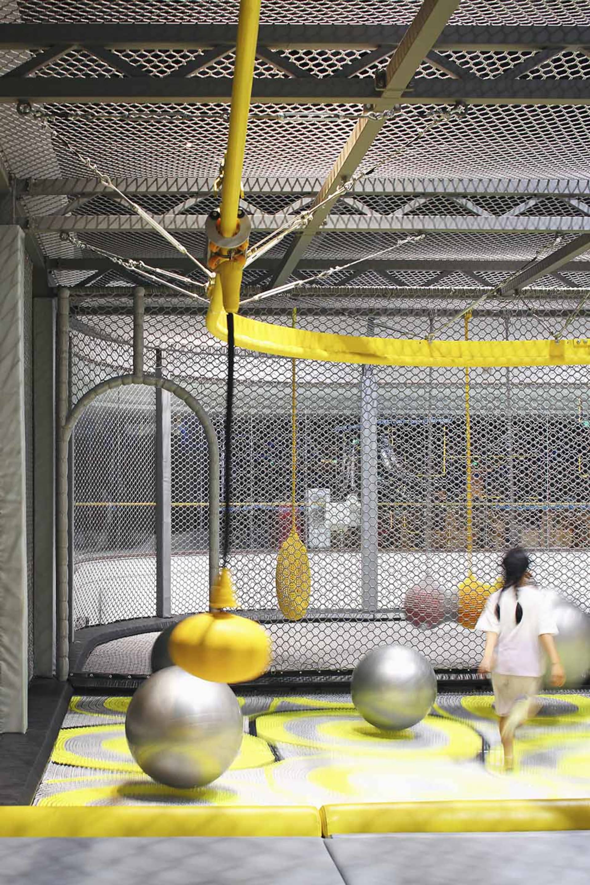 An industrial-style indoor playground with metal bars, foam spheres, and rubber flooring