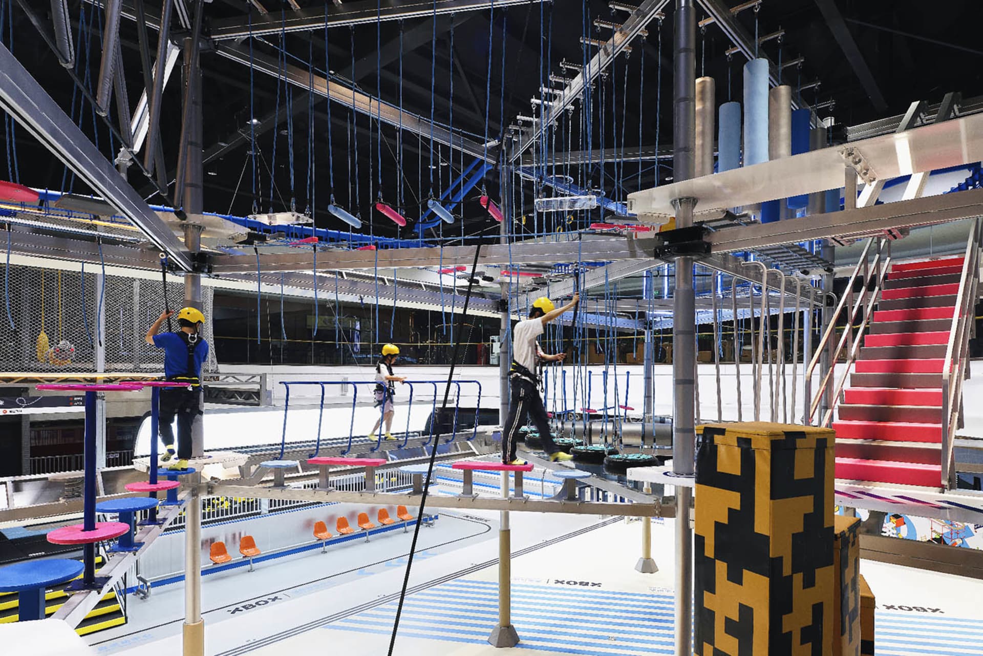 An industrial-styled playground with a metal rope course overhead