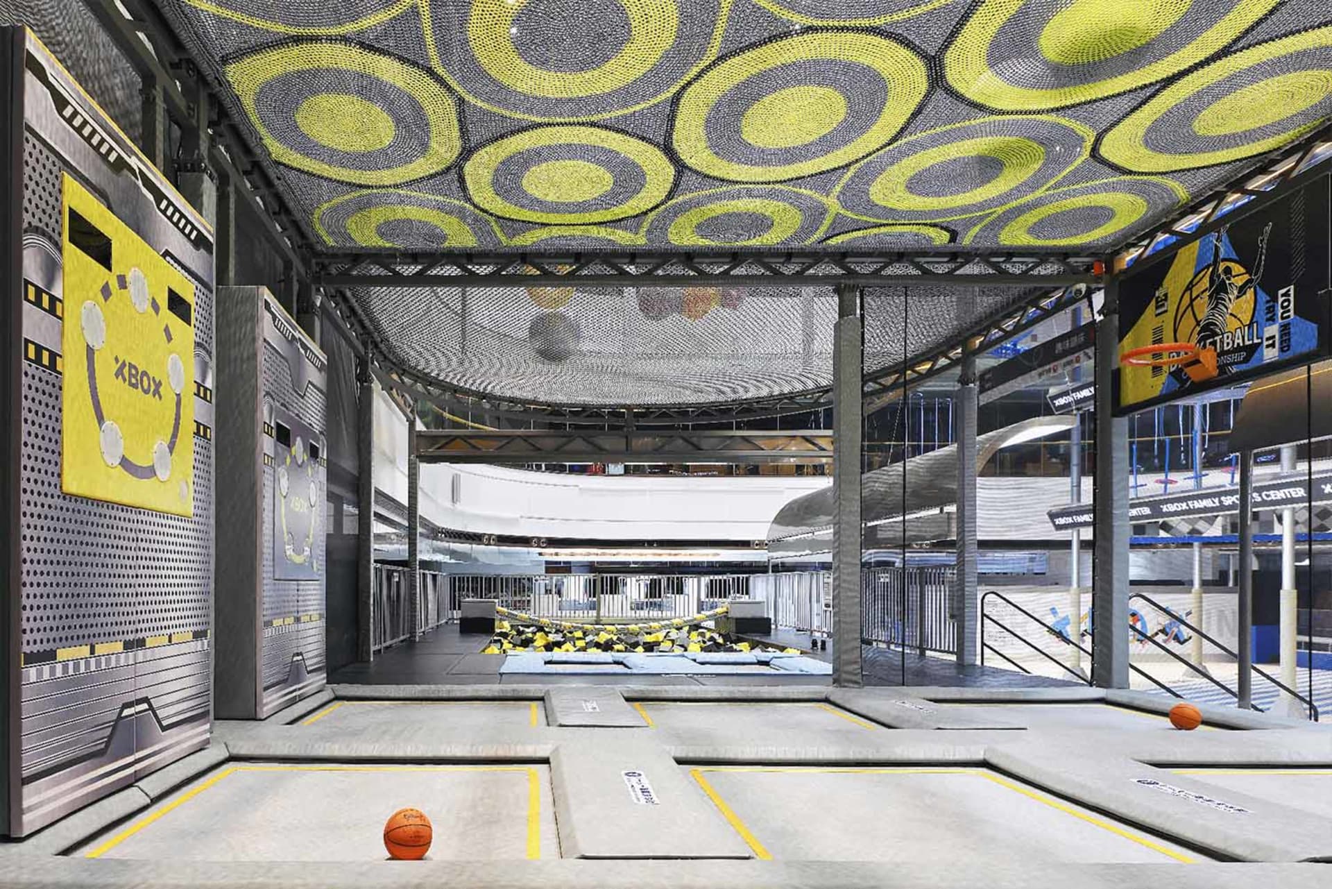 Indoor sports facility with industrial design features, concrete flooring, and mesh ceiling