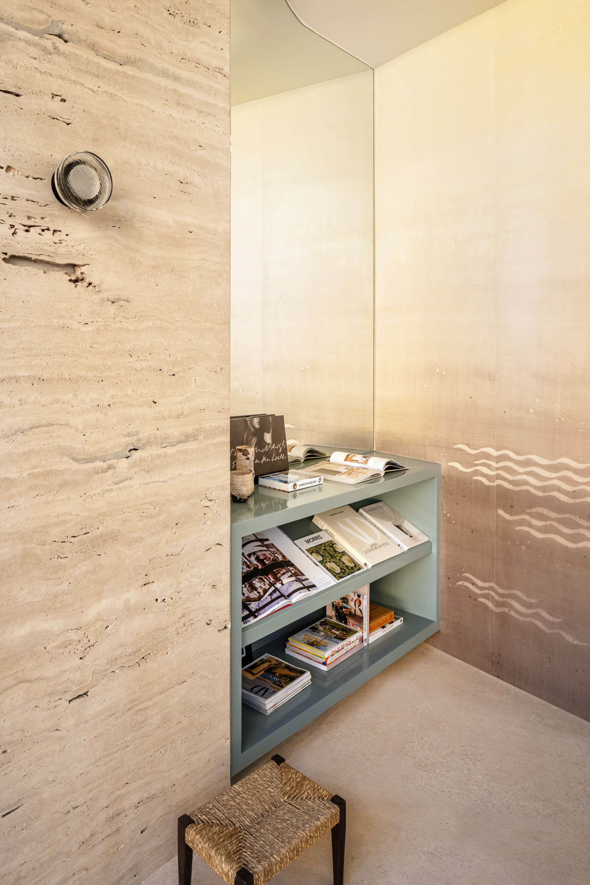 Modern-style concrete bookshelf with books and a wicker stool.