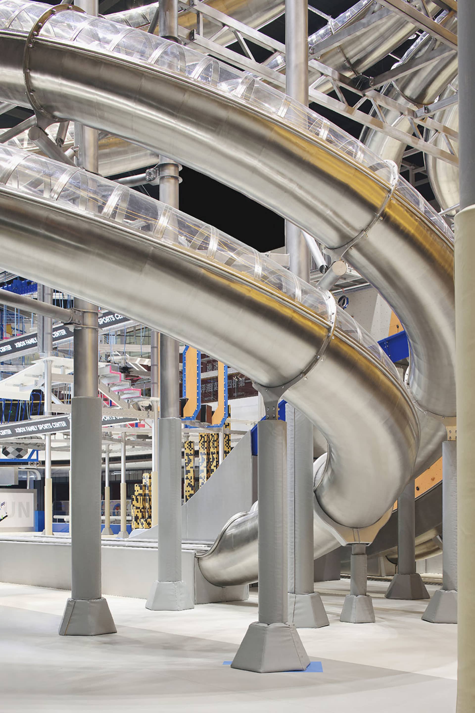Metallic slide structure with curved pathways and transparent barriers