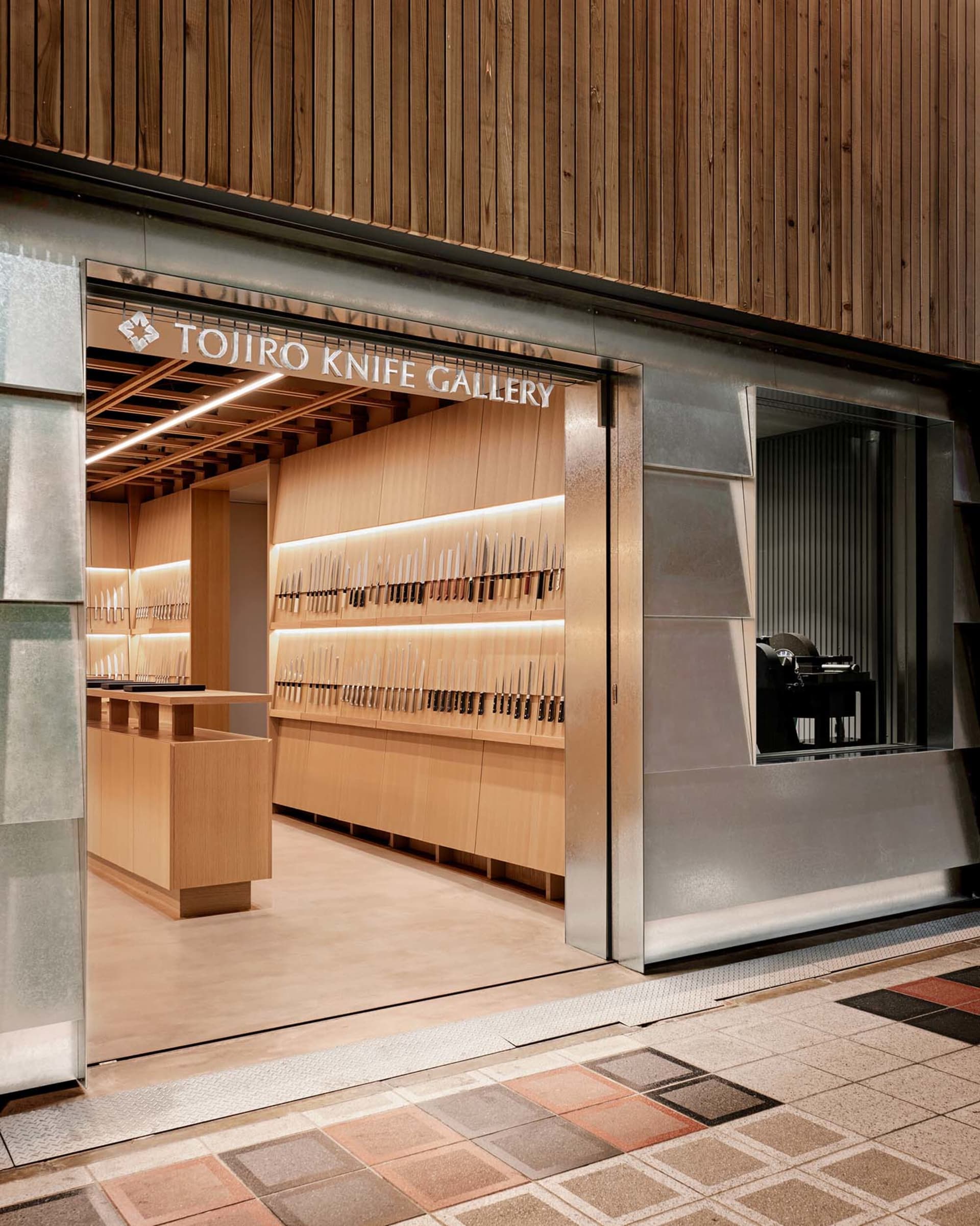 Modern storefront with a wall display of knives in a Tojiro Knife Gallery retail store
