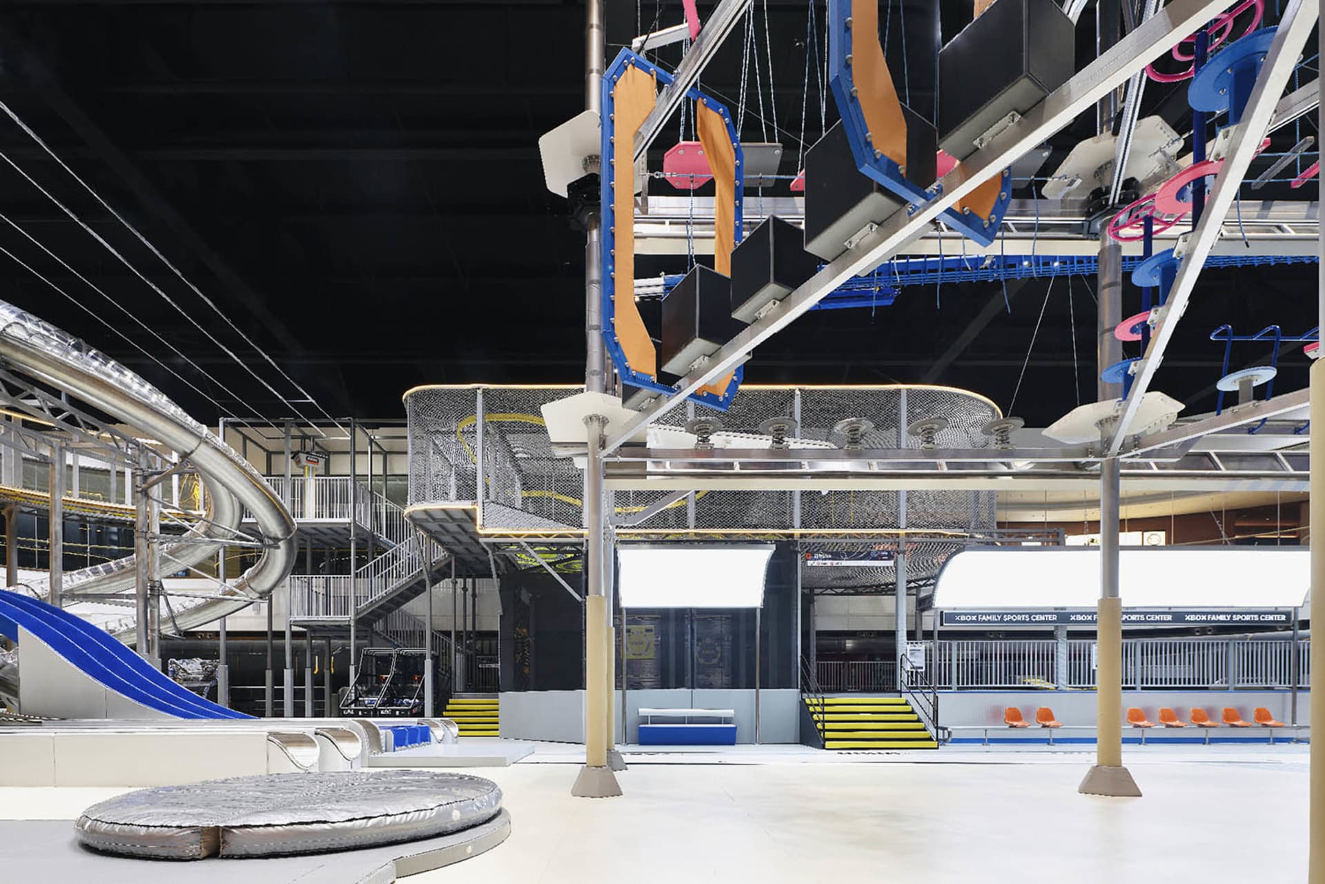 A large, indoor amusement area featuring metal structures, plastic playground equipment, and composite materials designed for
