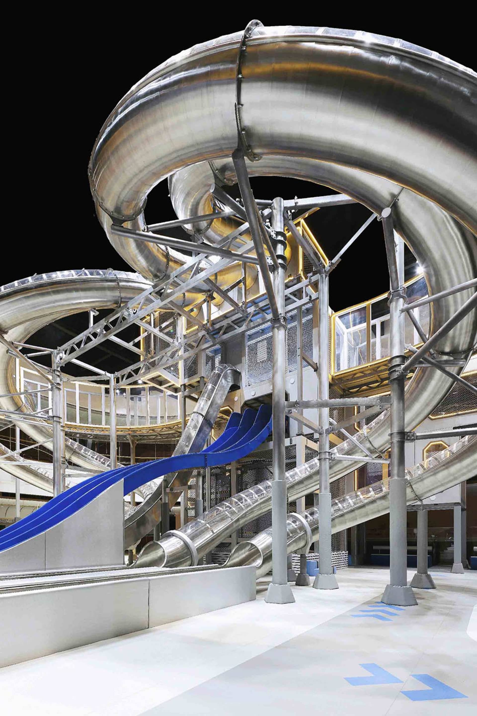 Metallic, industrial-style waterpark slide with blue water tubes and steel structure