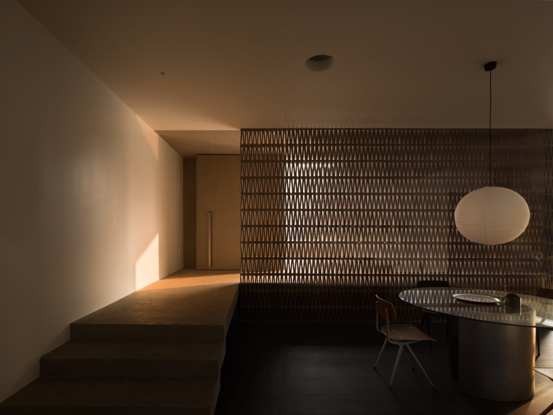 簡約餐廳內擺放木質家具,設有圓形玻璃餐桌與燈具。