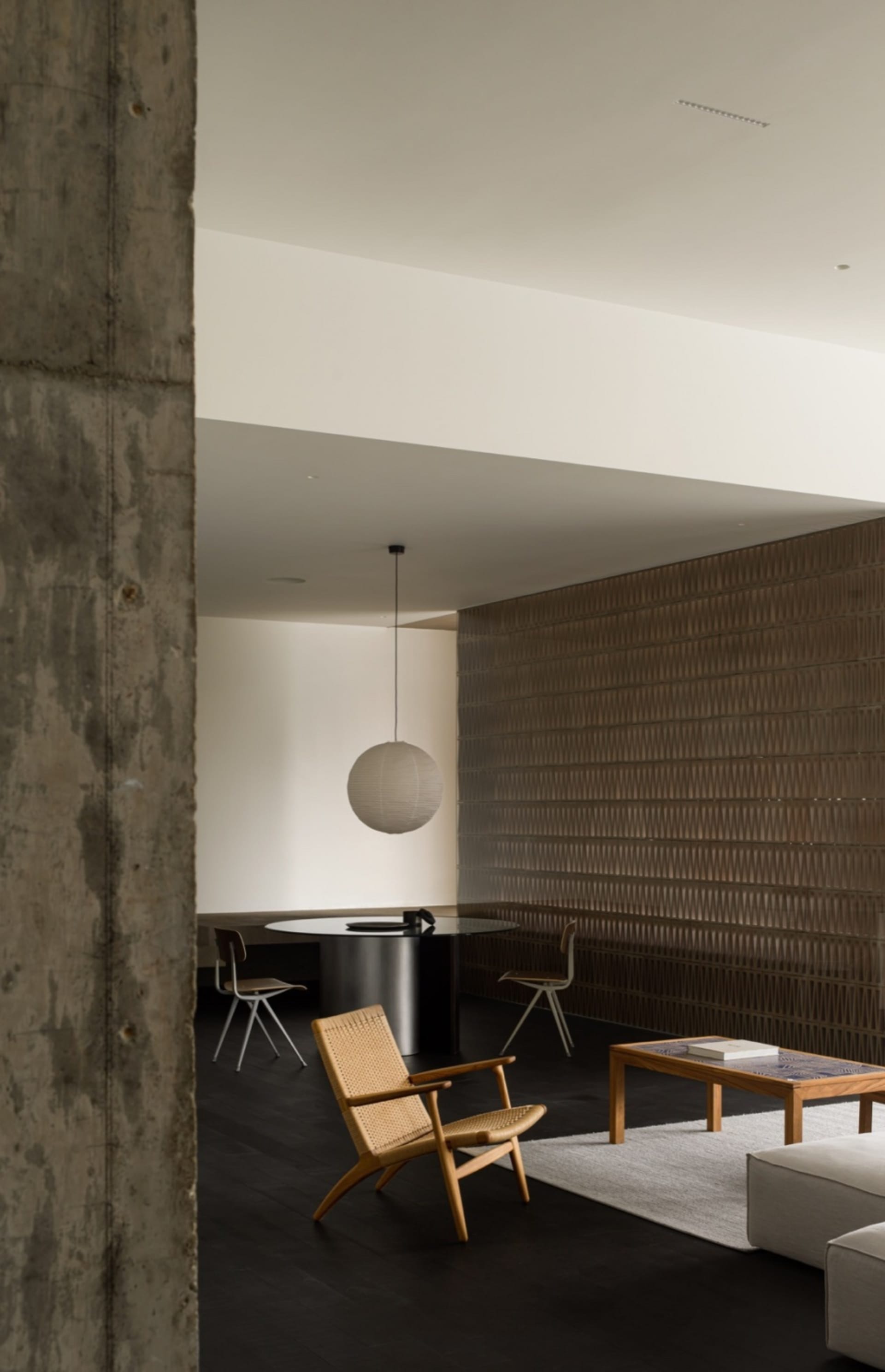 A minimalist living room featuring a concrete wall, wooden floor, and bamboo furniture.