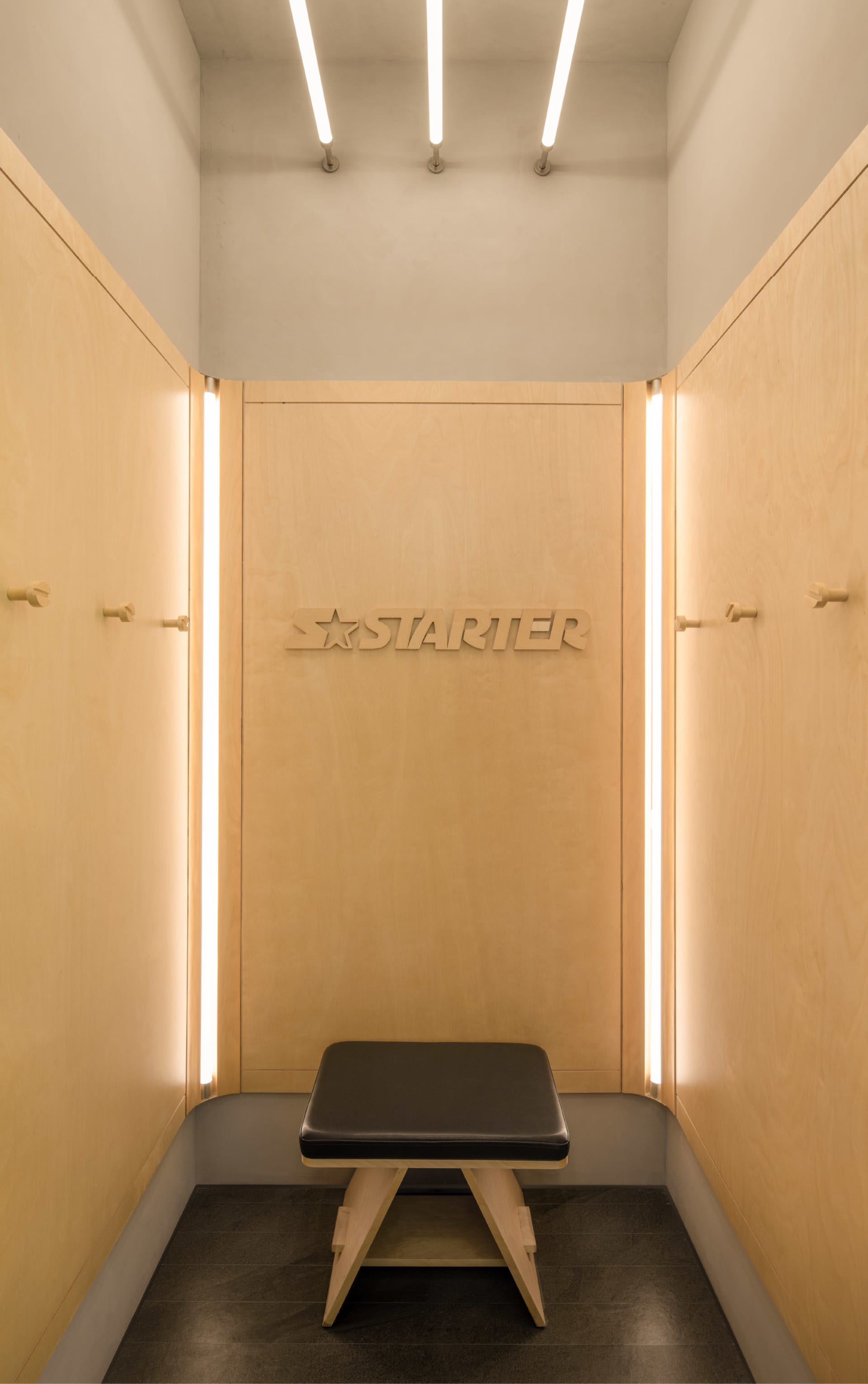 Modern minimalist clothing retail store with wooden walls and illuminated signage.