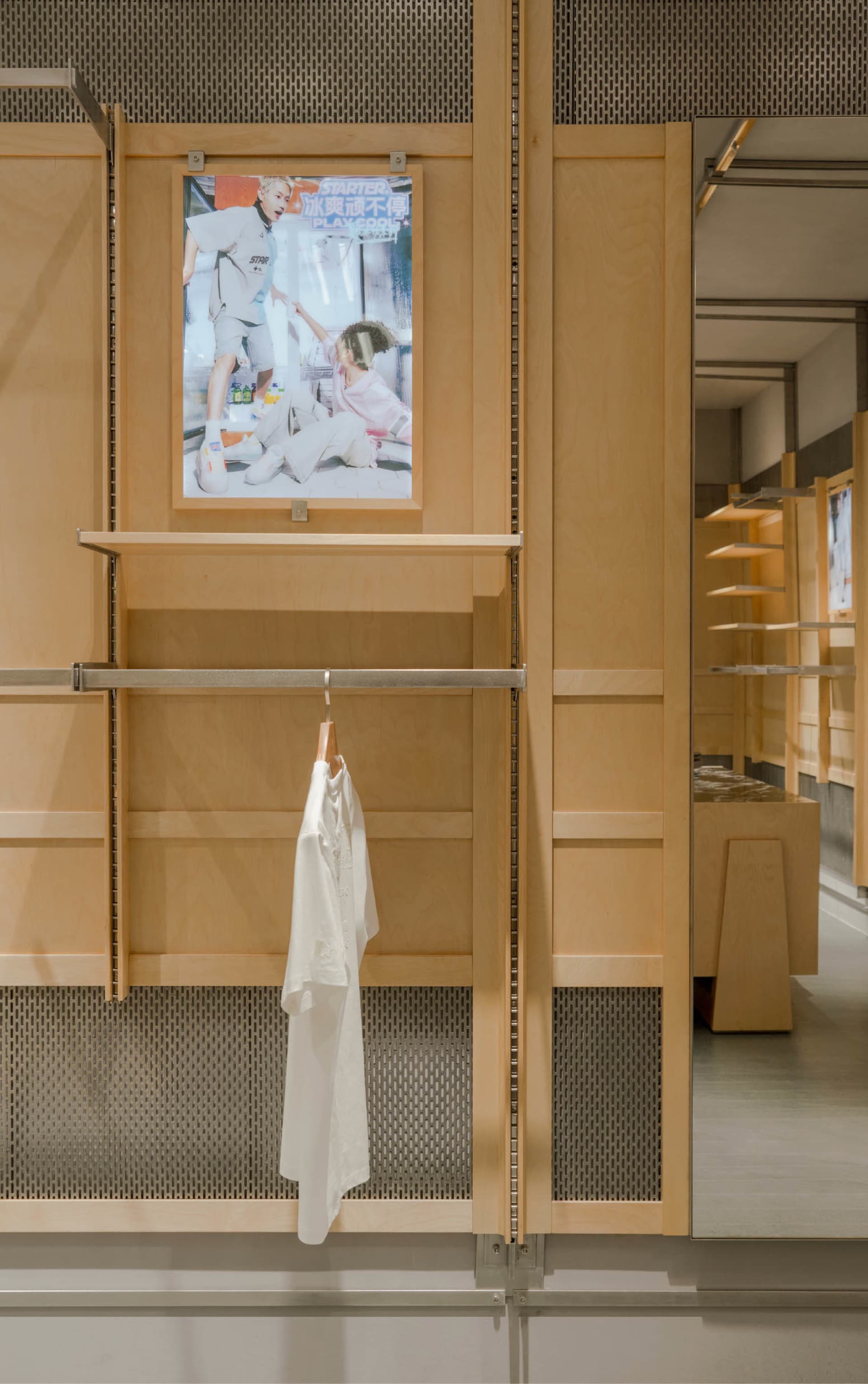 A retail shop interior featuring wooden shelves and a hanging shirt.