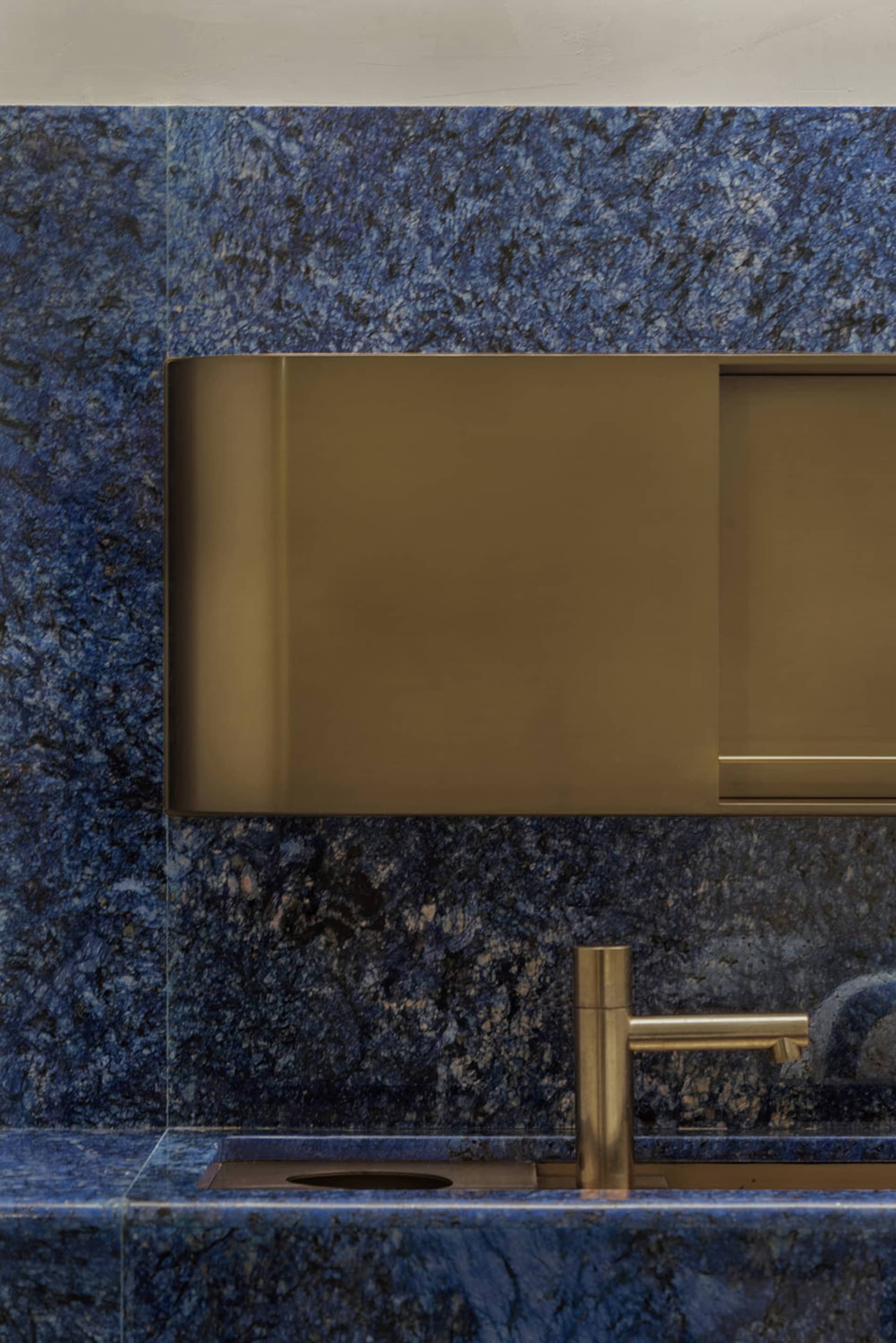 Modern bathroom featuring blue granite and brass faucet
