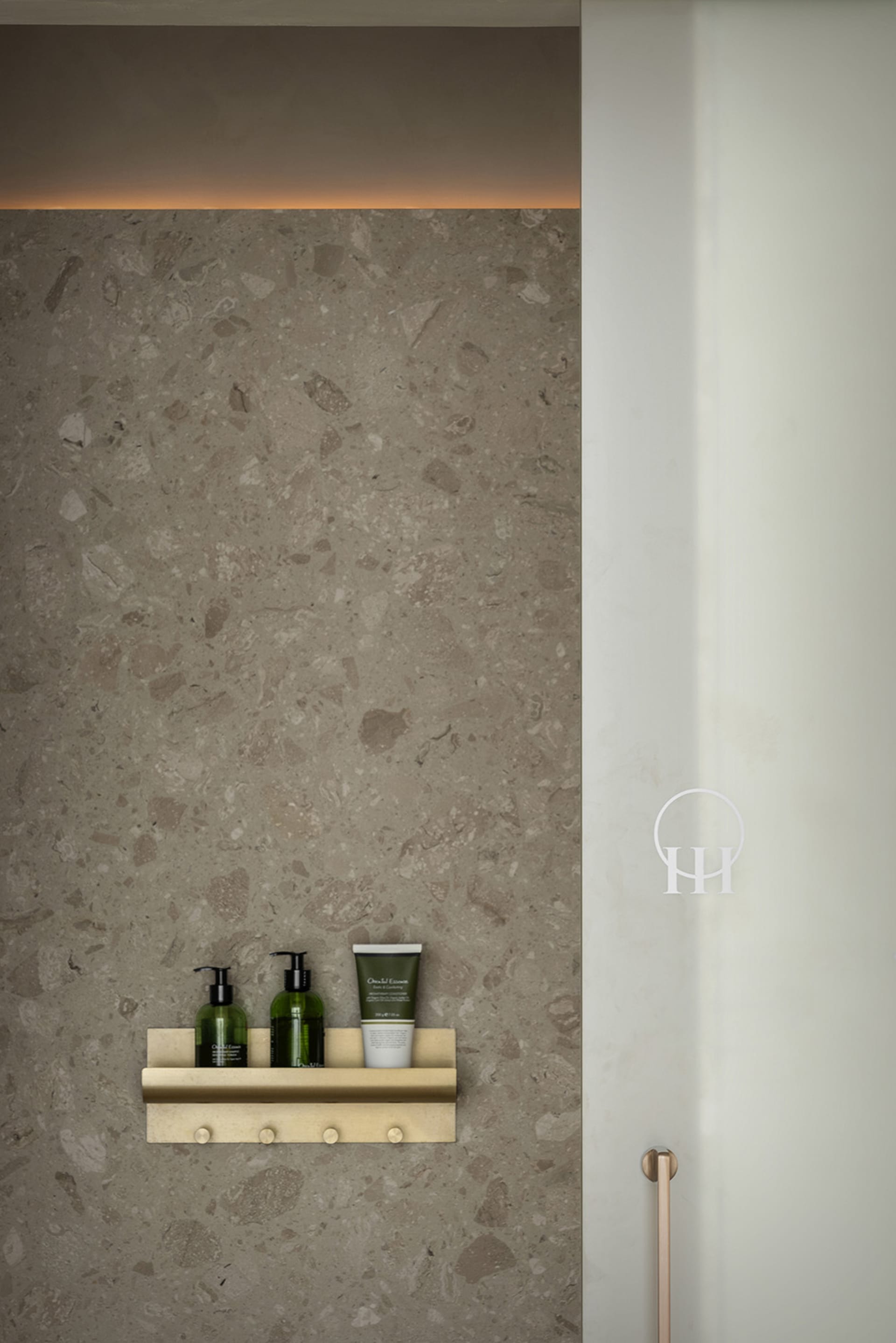 A minimalist bathroom showcases a concrete shelf with various toiletries.