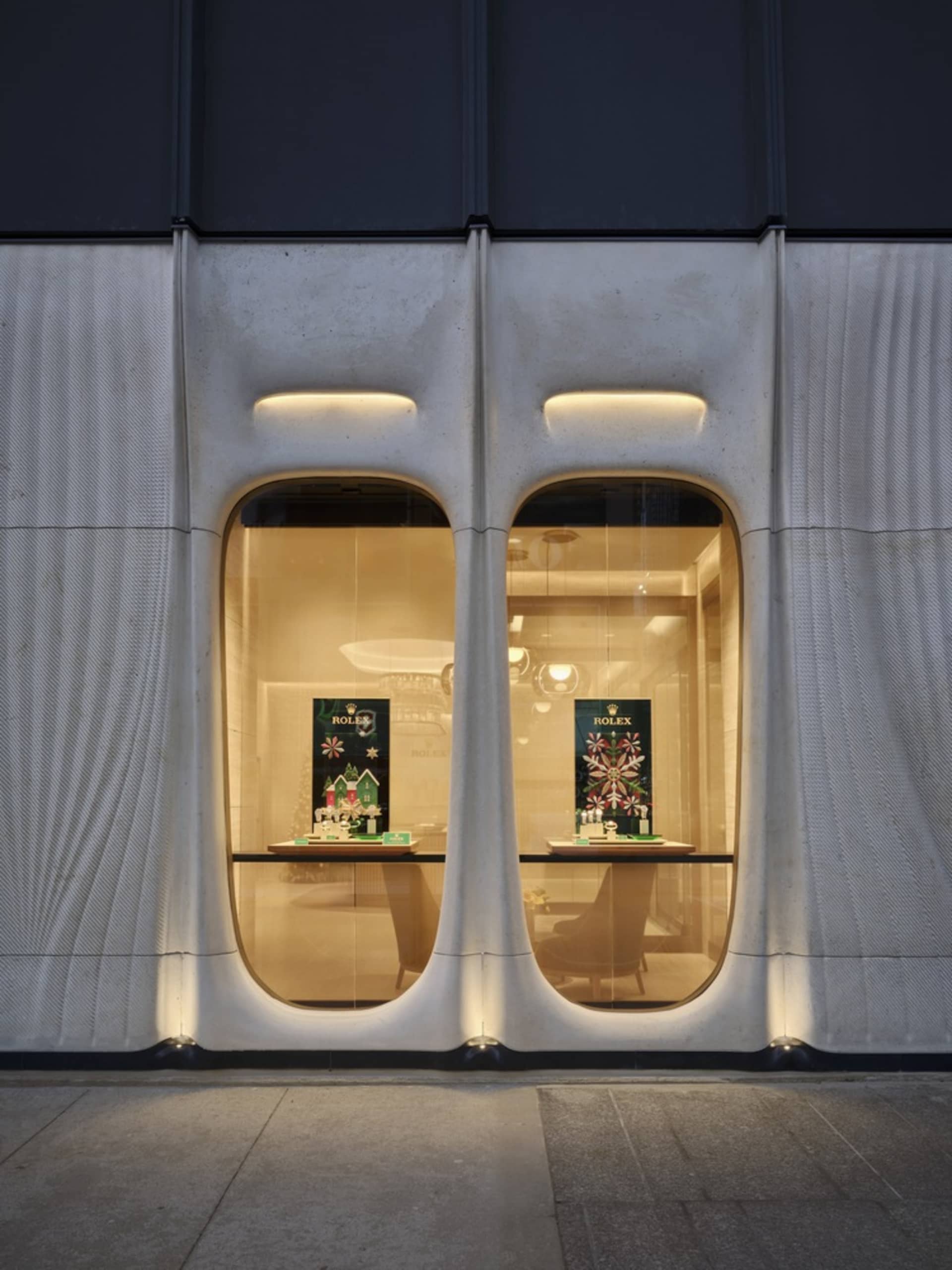 A modern storefront featuring glass display windows with illuminated signage and showcases.