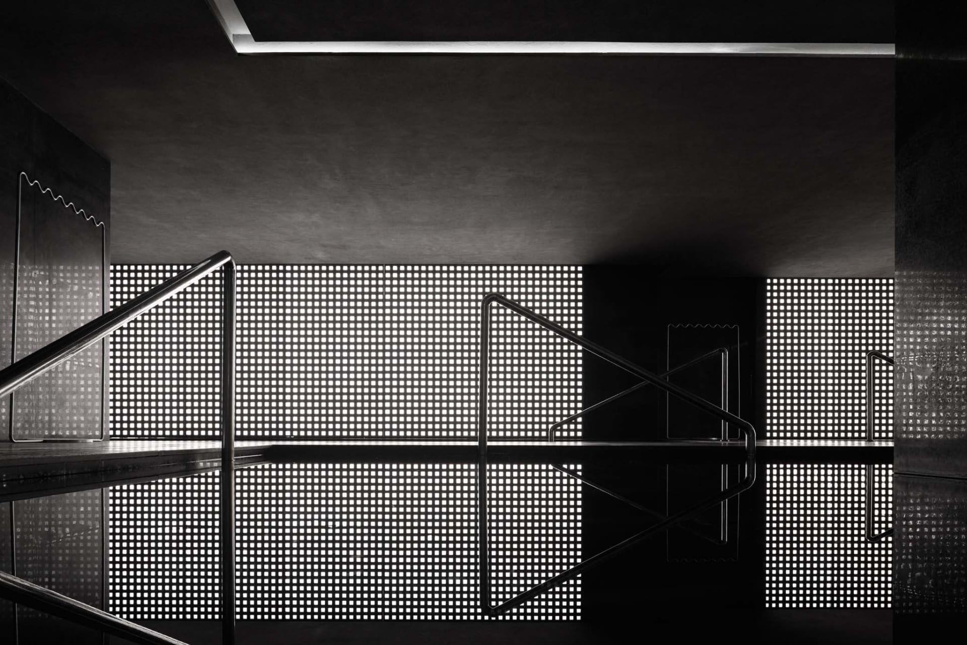 Modern minimalist interior with steel and concrete elements, featuring perforated glass and geometric design.