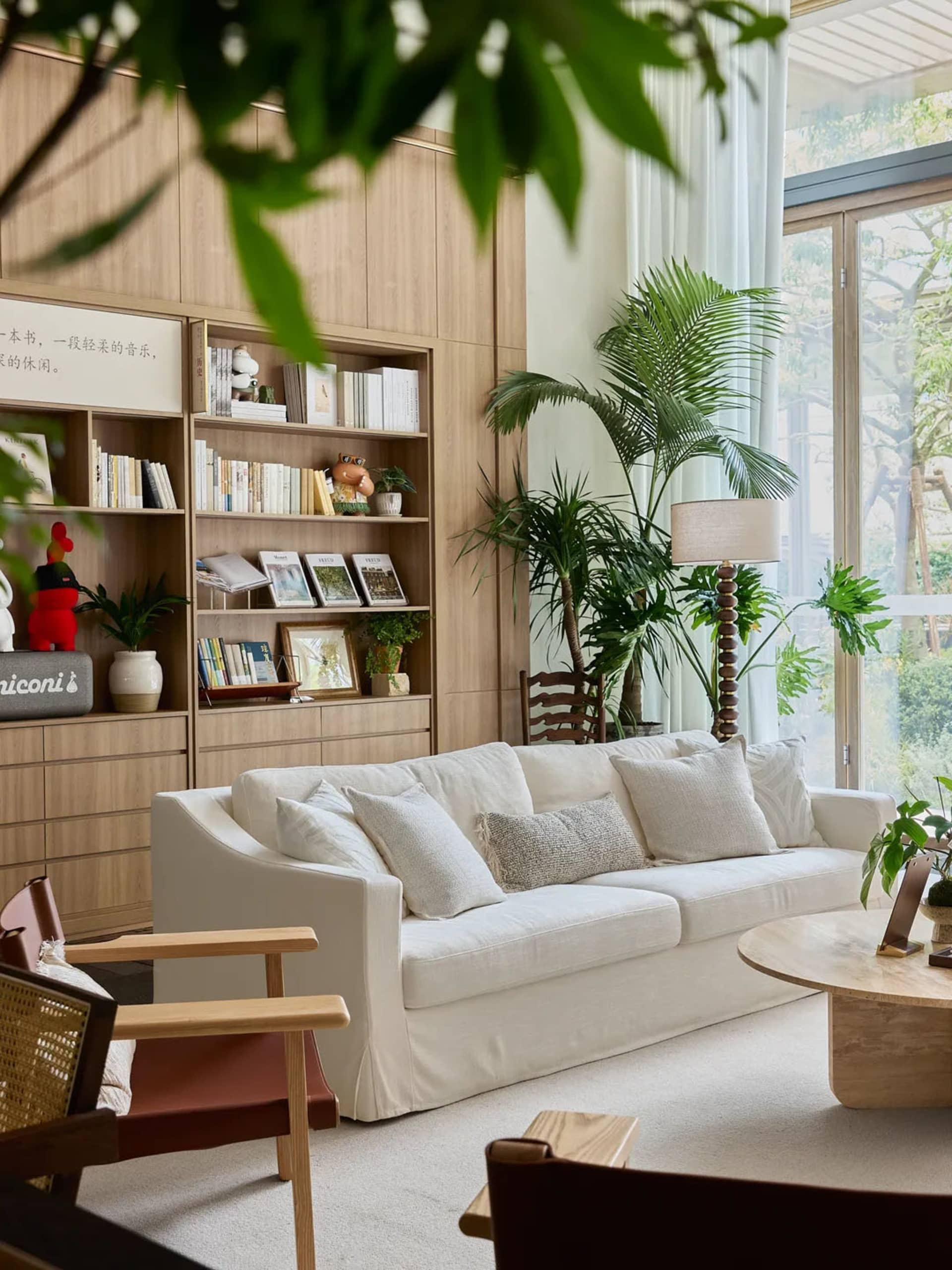 Modern living room featuring white furniture, wooden shelves, and potted plants