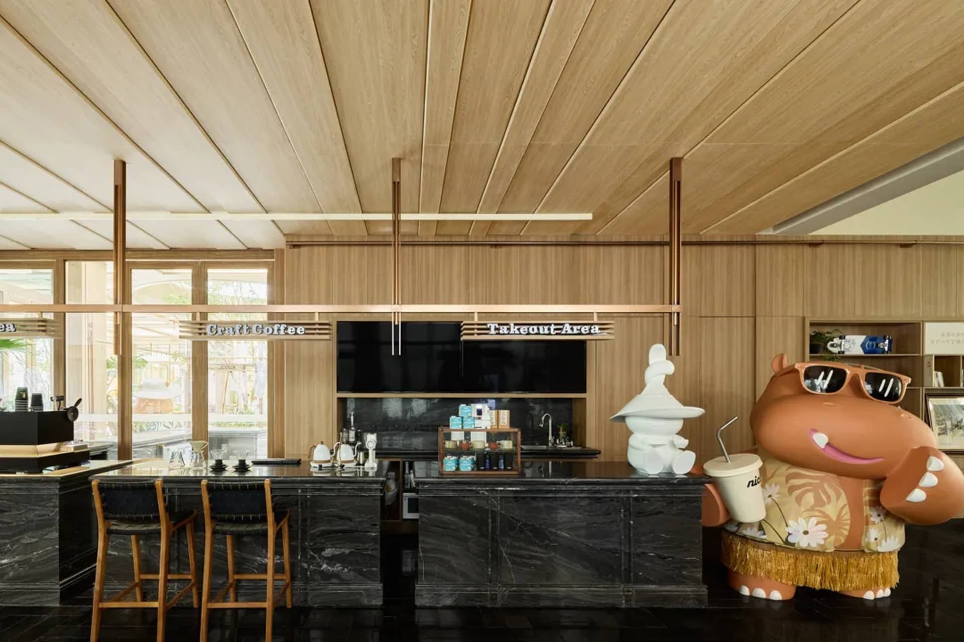 A modern bar with a wooden and marble interior, featuring stools, stools, and a large hippo figure.