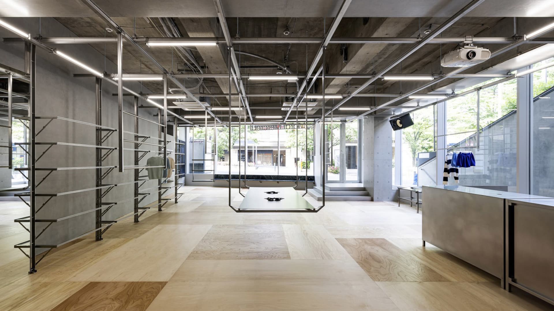 Modern retail space with concrete walls, metal shelving, and wooden flooring.
