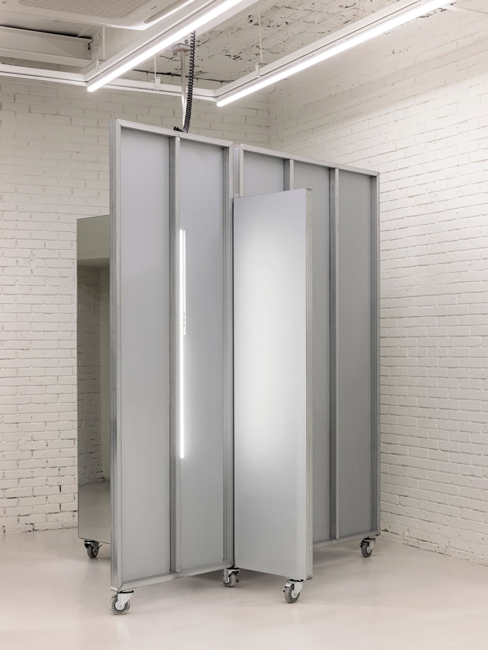 A minimalist metal installation featuring translucent panels and a neon light strip.