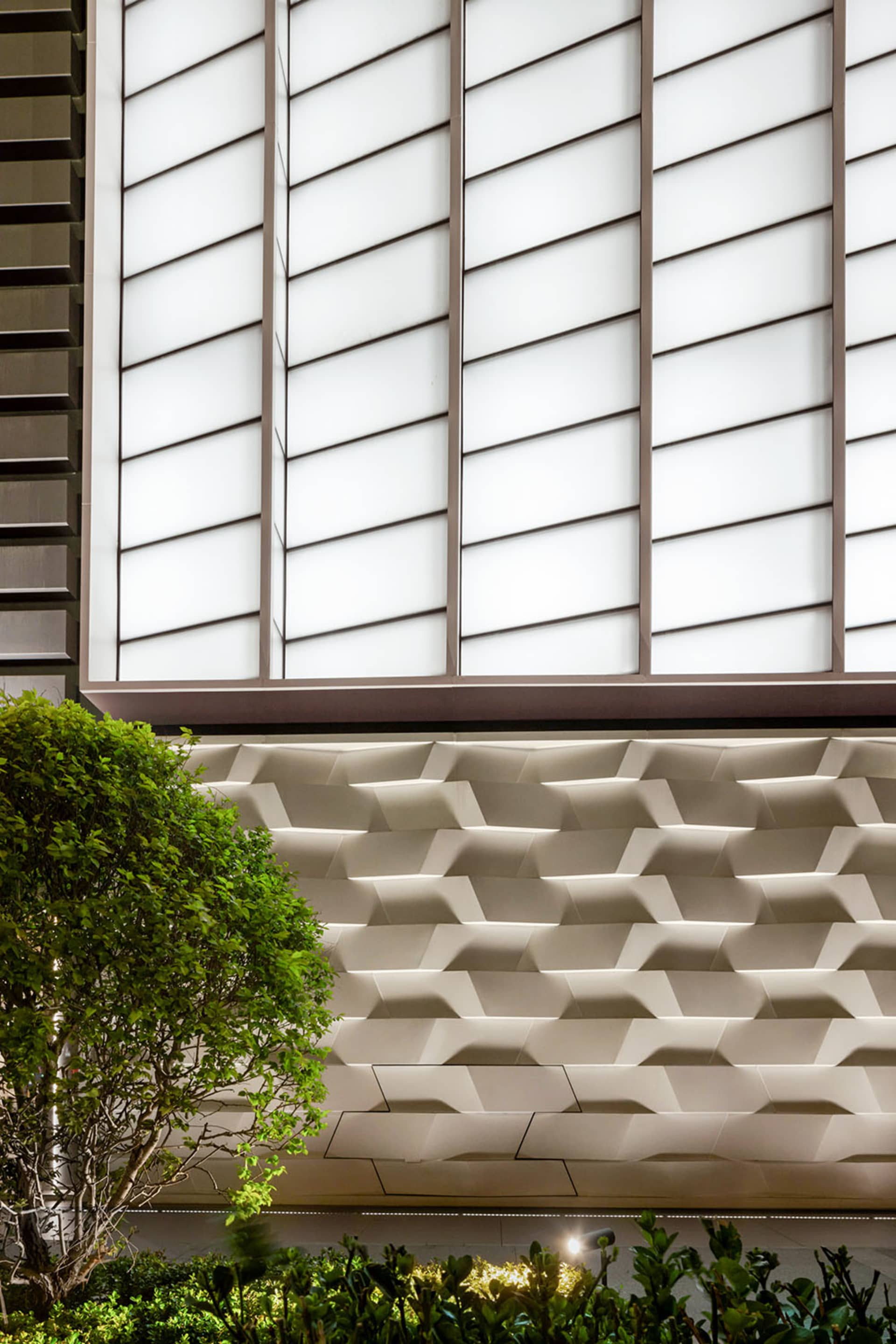 Modern architectural design featuring a textured concrete exterior with large glass windows.