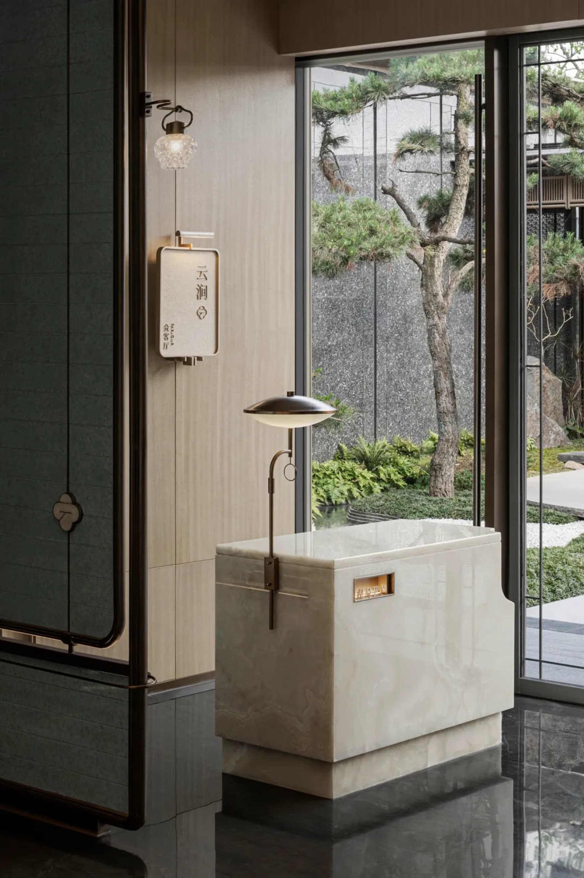 Modern bathroom featuring a marble tub and metal accents surrounded by green leaves and trees.