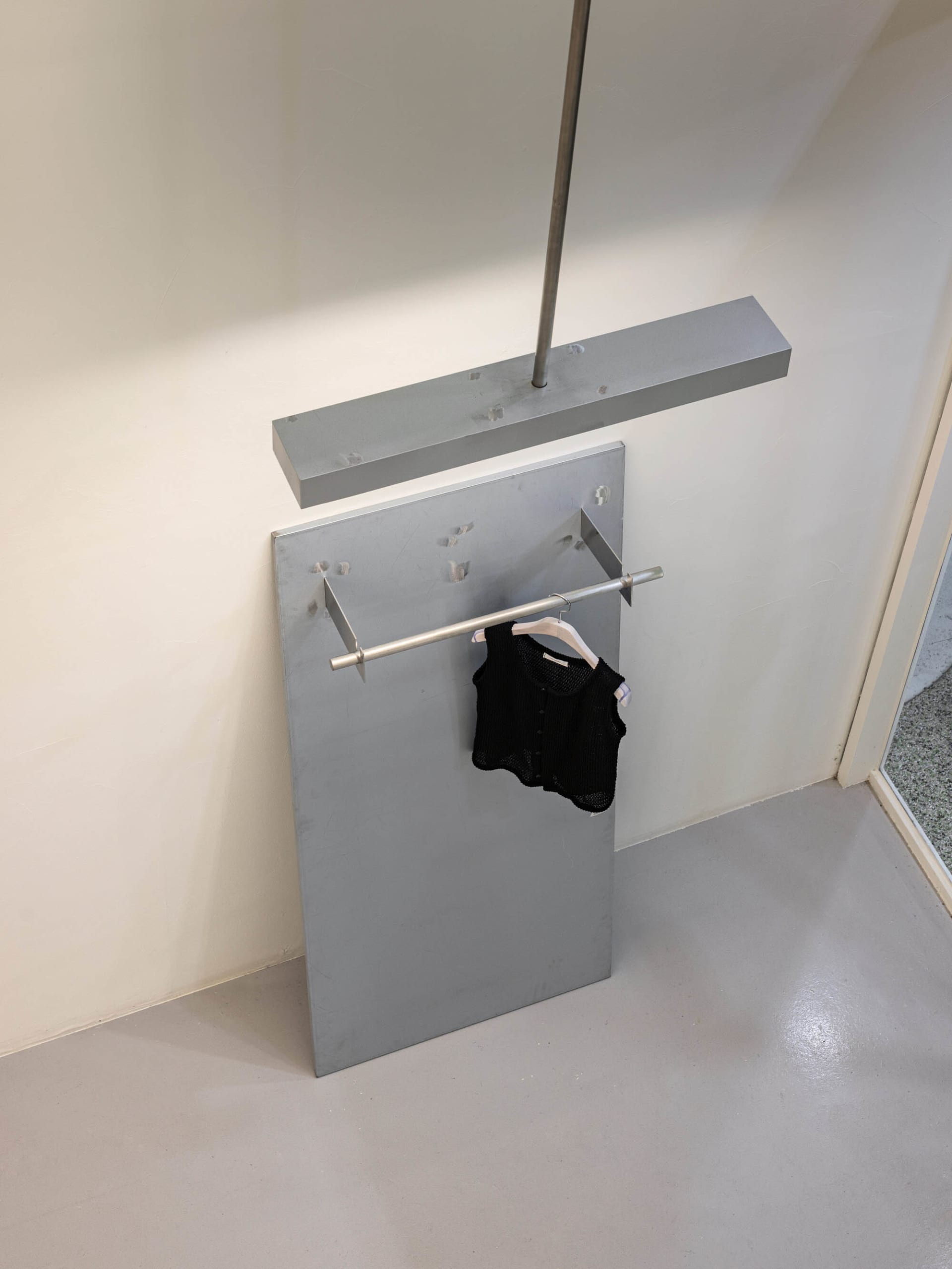 Metal clothing rack with a black knitted vest hanging.
