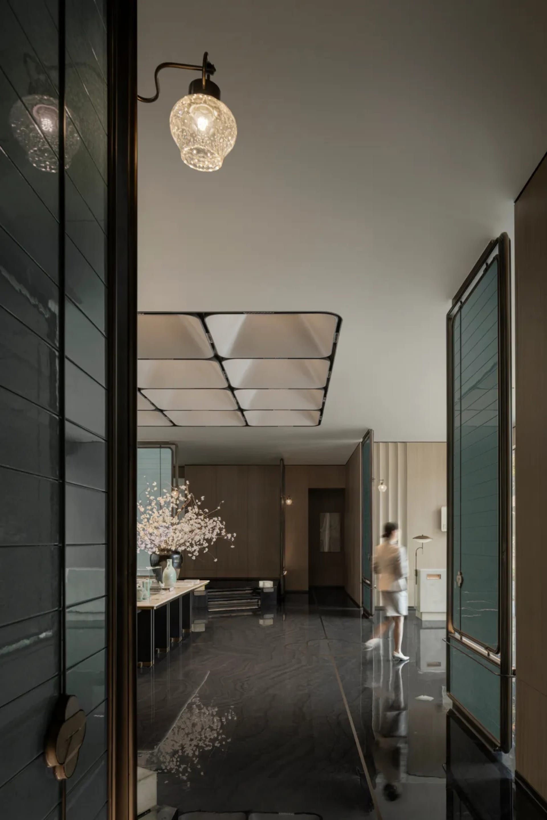 A minimalist interior featuring concrete walls and flooring, with a person walking through the space.