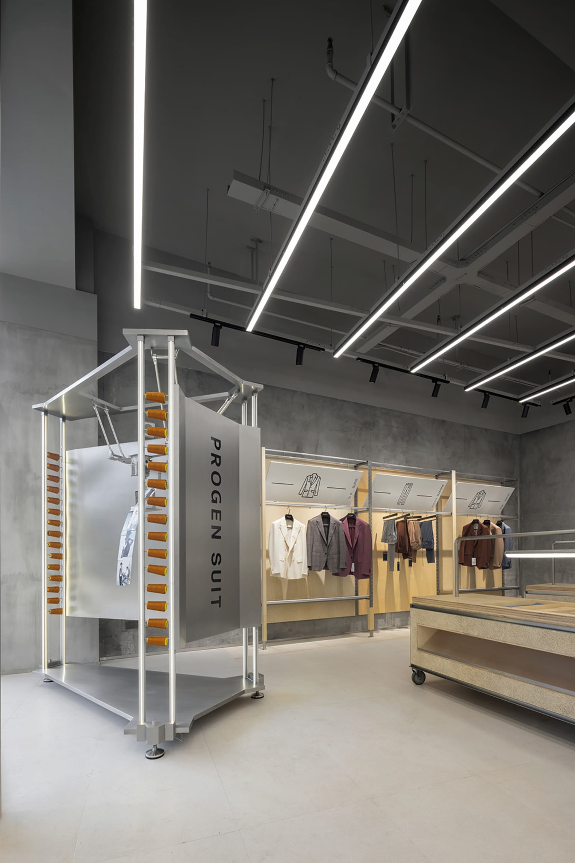 A modern retail shop featuring a metal and concrete interior displaying suits.