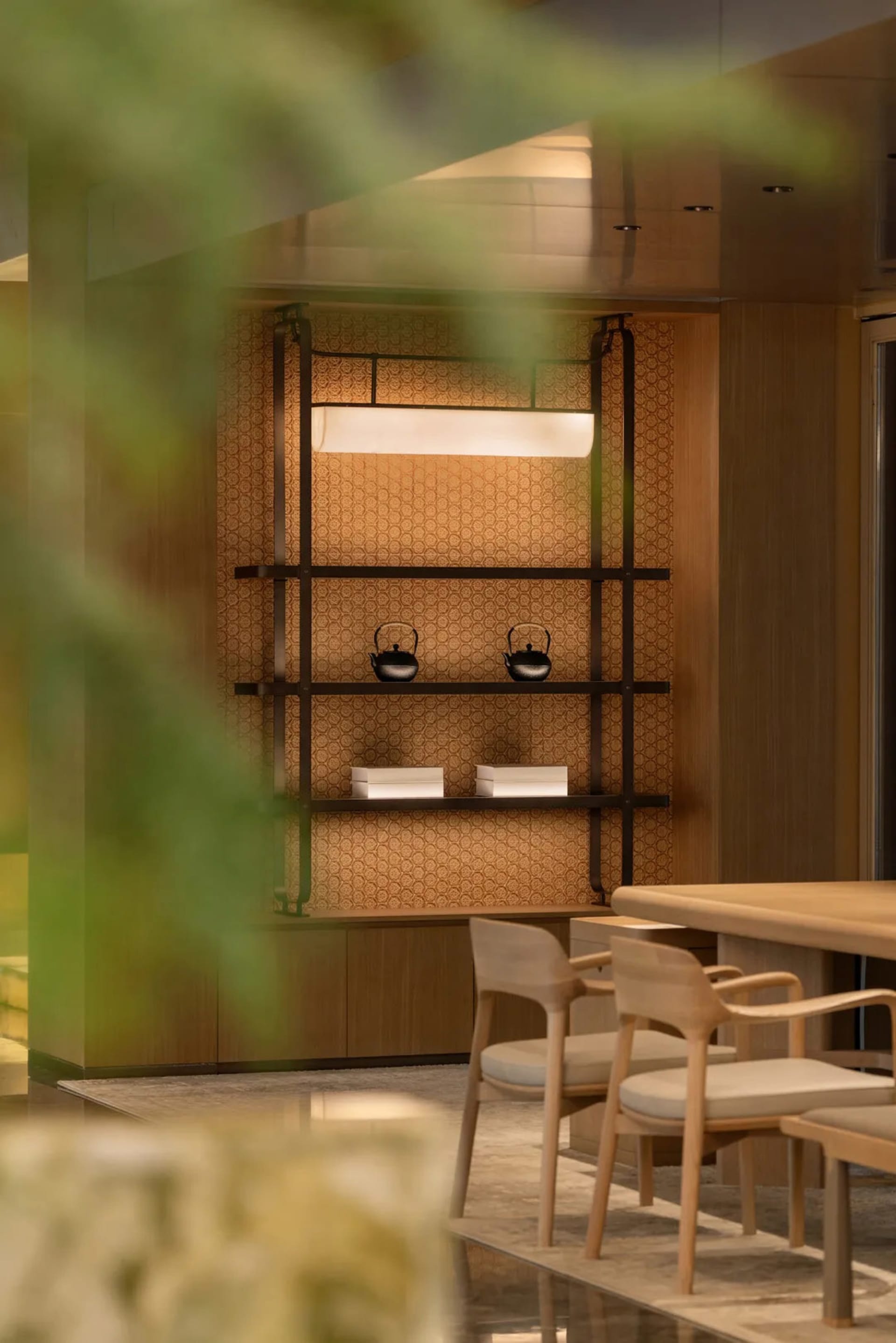 A modern dining room featuring wood shelves with kettles and boxes.