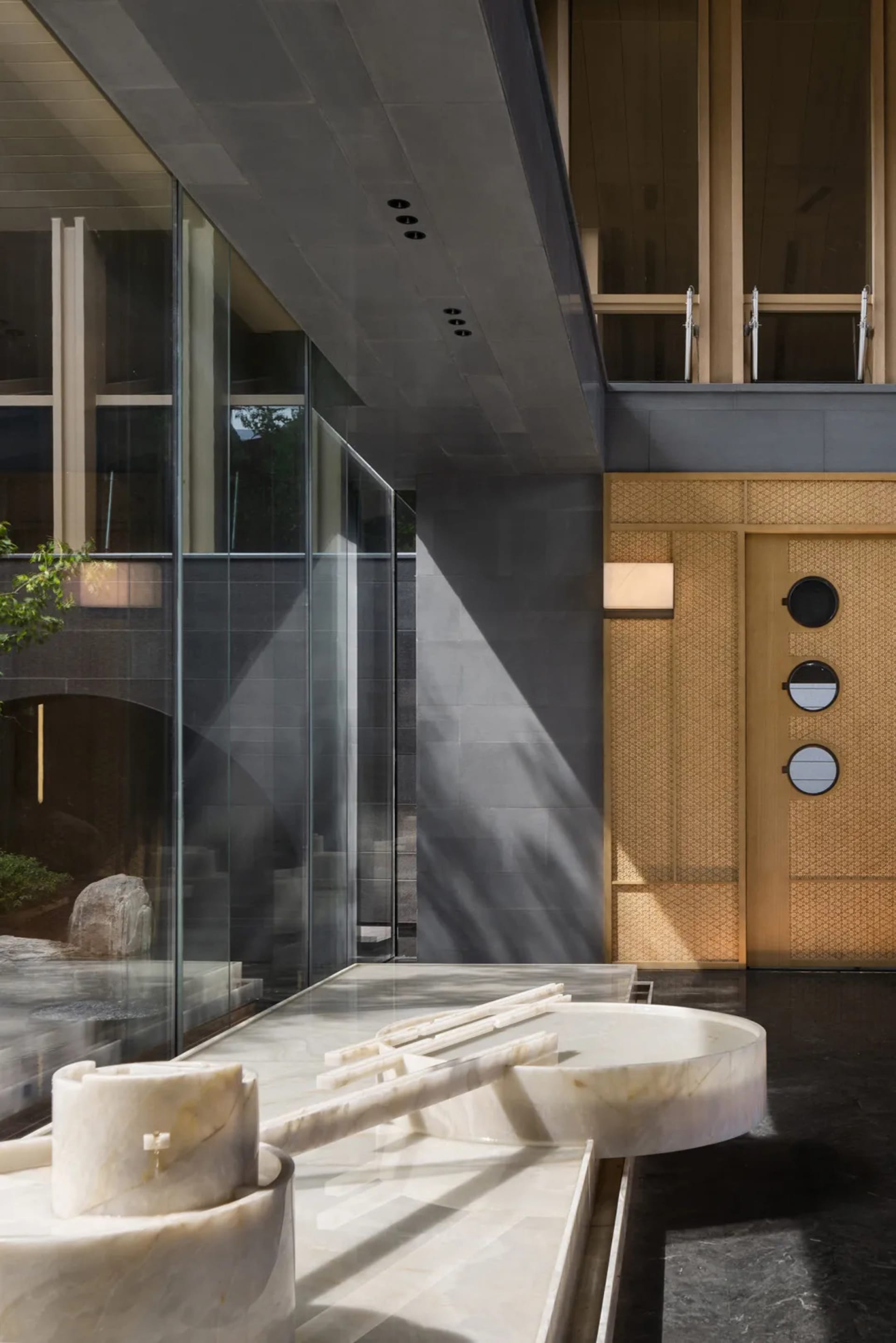 A modern interior space featuring a marble fountain, with a mix of glass and wooden elements, and a sleek, contemporary desig