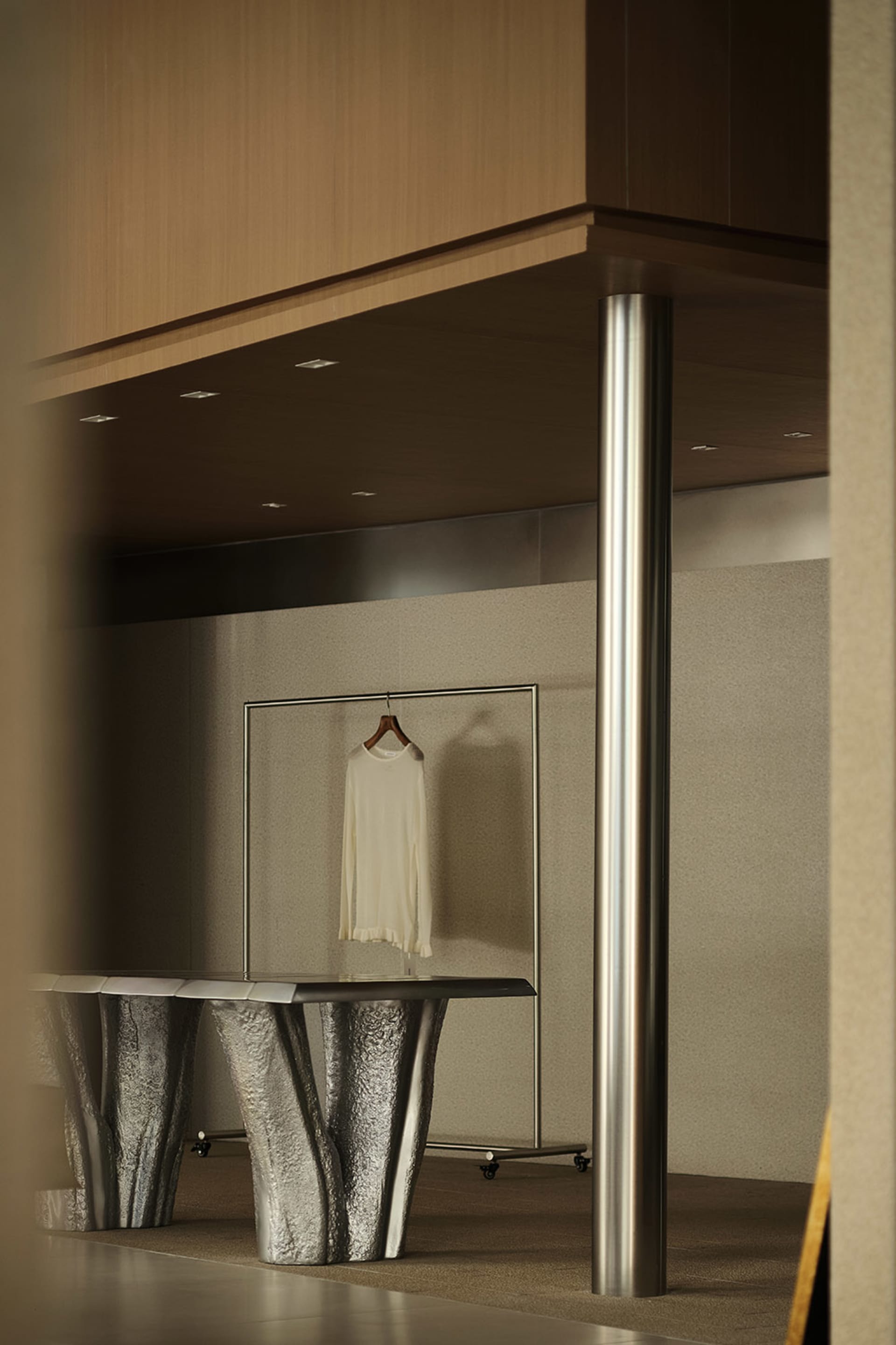 Metallic table in a retail space with a white garment on a hanger.