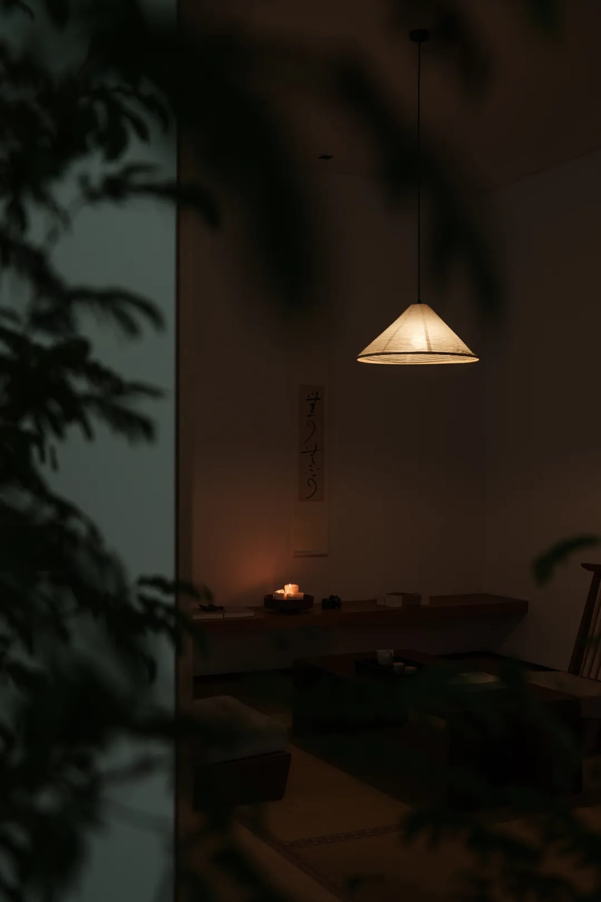 簡約舒適的休憩區,配有紙燈罩、蠟燭,以及牆上懸掛的傳統日式書法卷軸。