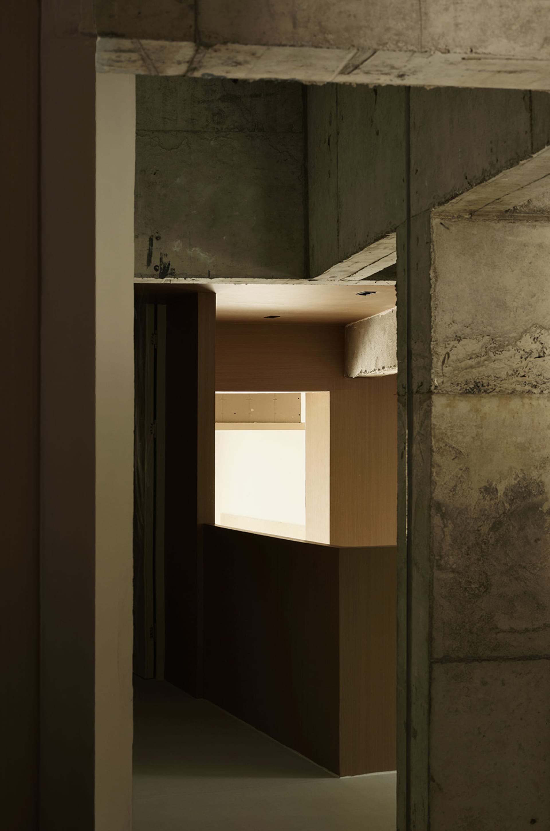 A minimalist interior space with concrete walls and ceiling, featuring a bright light source.