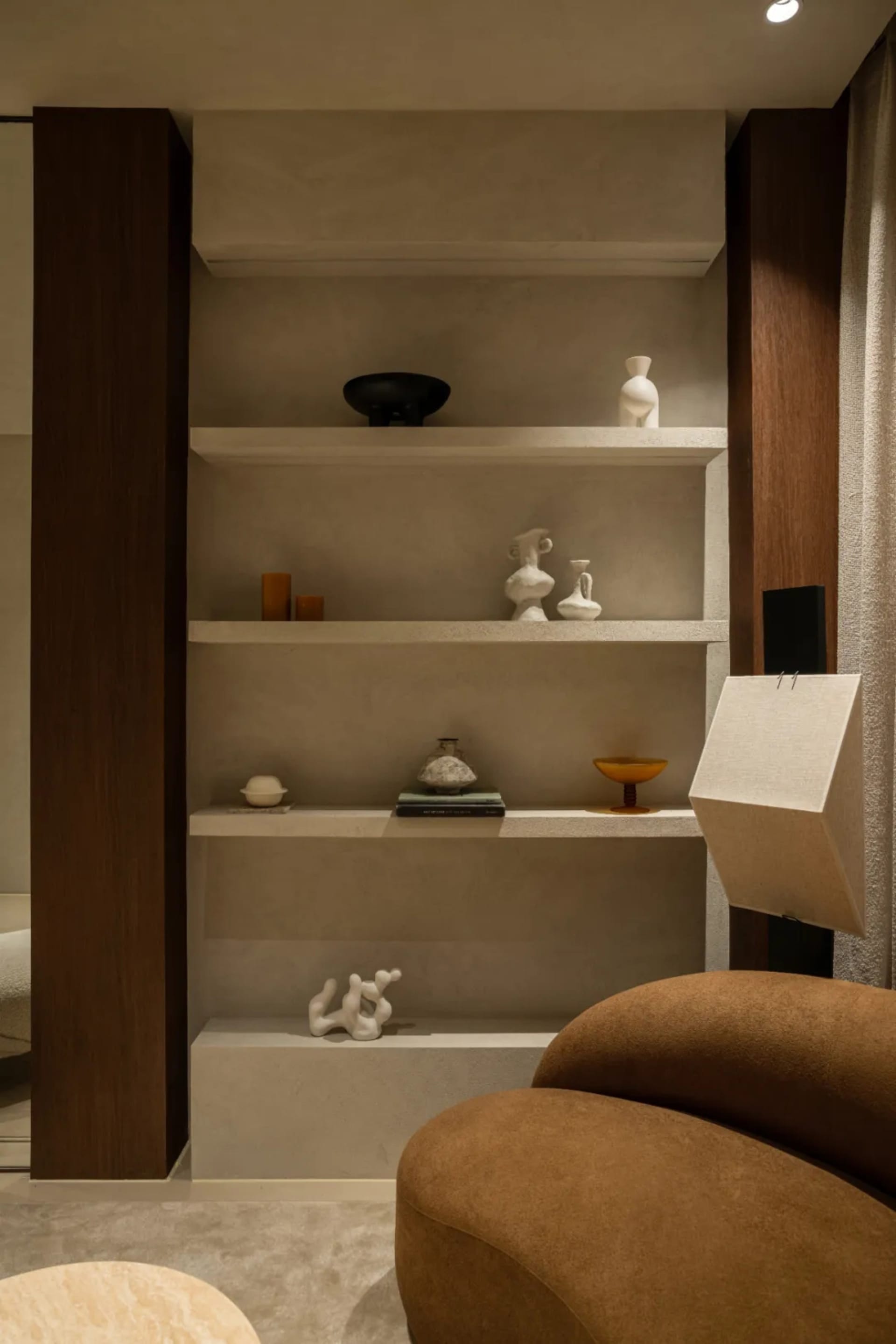 Furniture and decor items arranged on a concrete shelving unit in a minimalist living room.