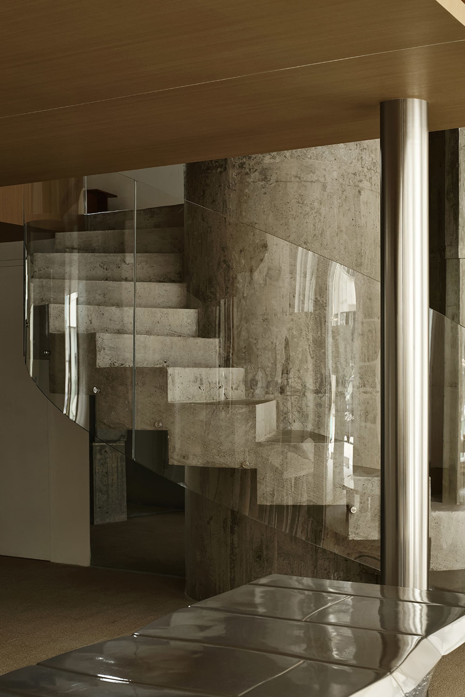Modern industrial staircase featuring concrete steps and glass railings.