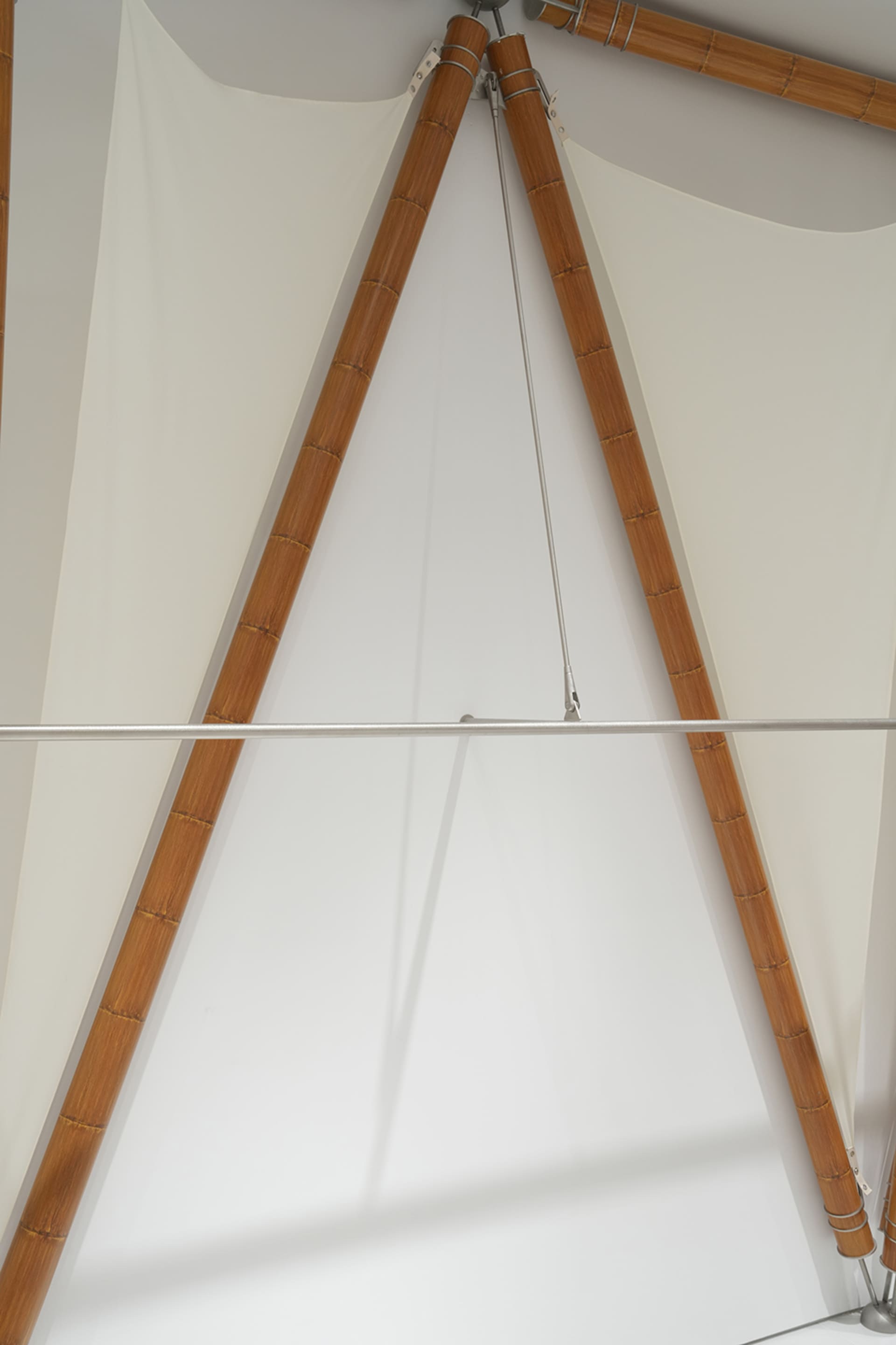 An architectural space with white cloth panels supported by wooden trusses.