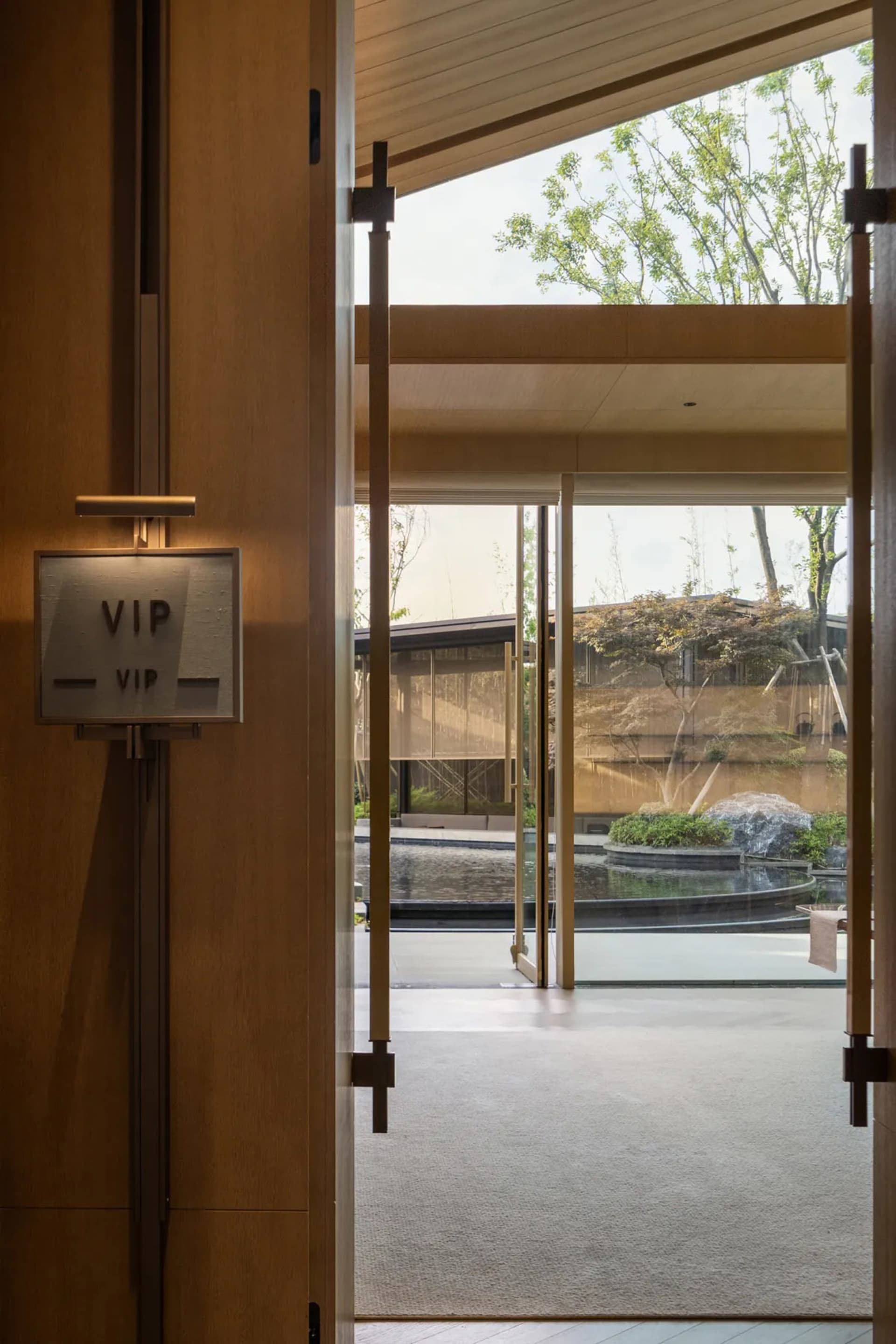 A modern hotel lobby featuring glass walls and a serene outdoor view.