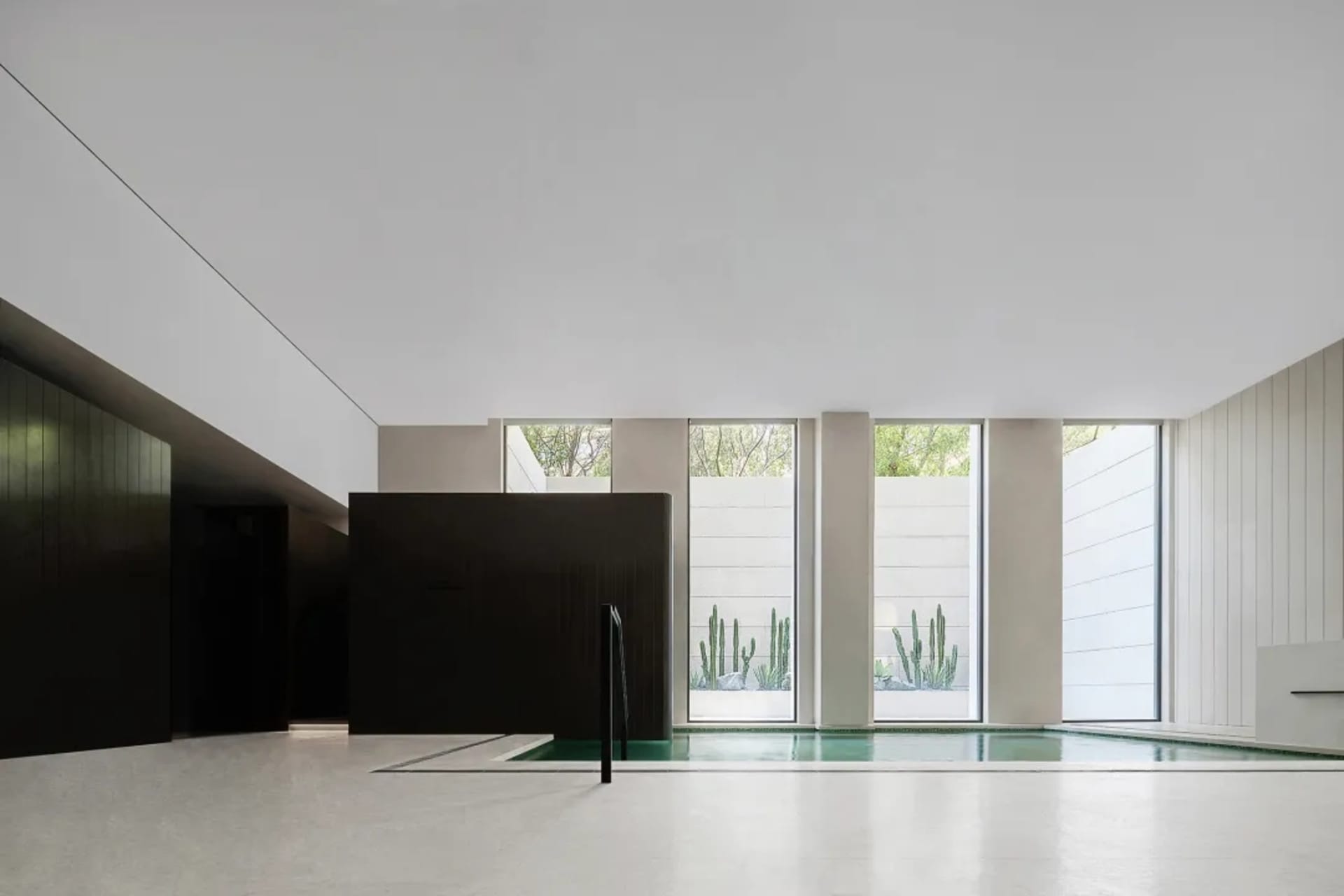 An industrial-style pool enclosed by concrete walls and large windows, featuring a minimalist design with a modern aesthetic.