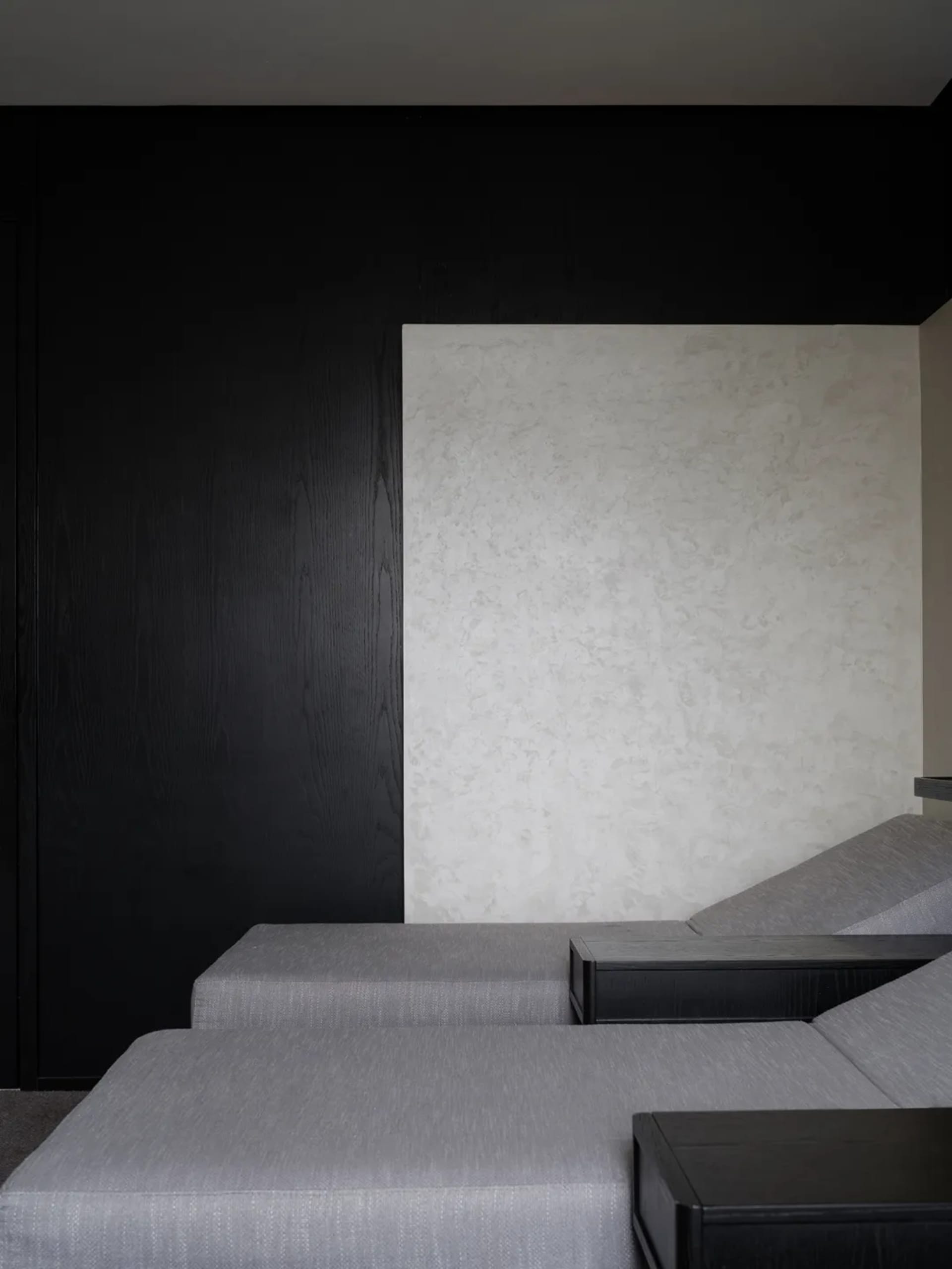 A minimalist sofa with black and white upholstery against a textured wall.