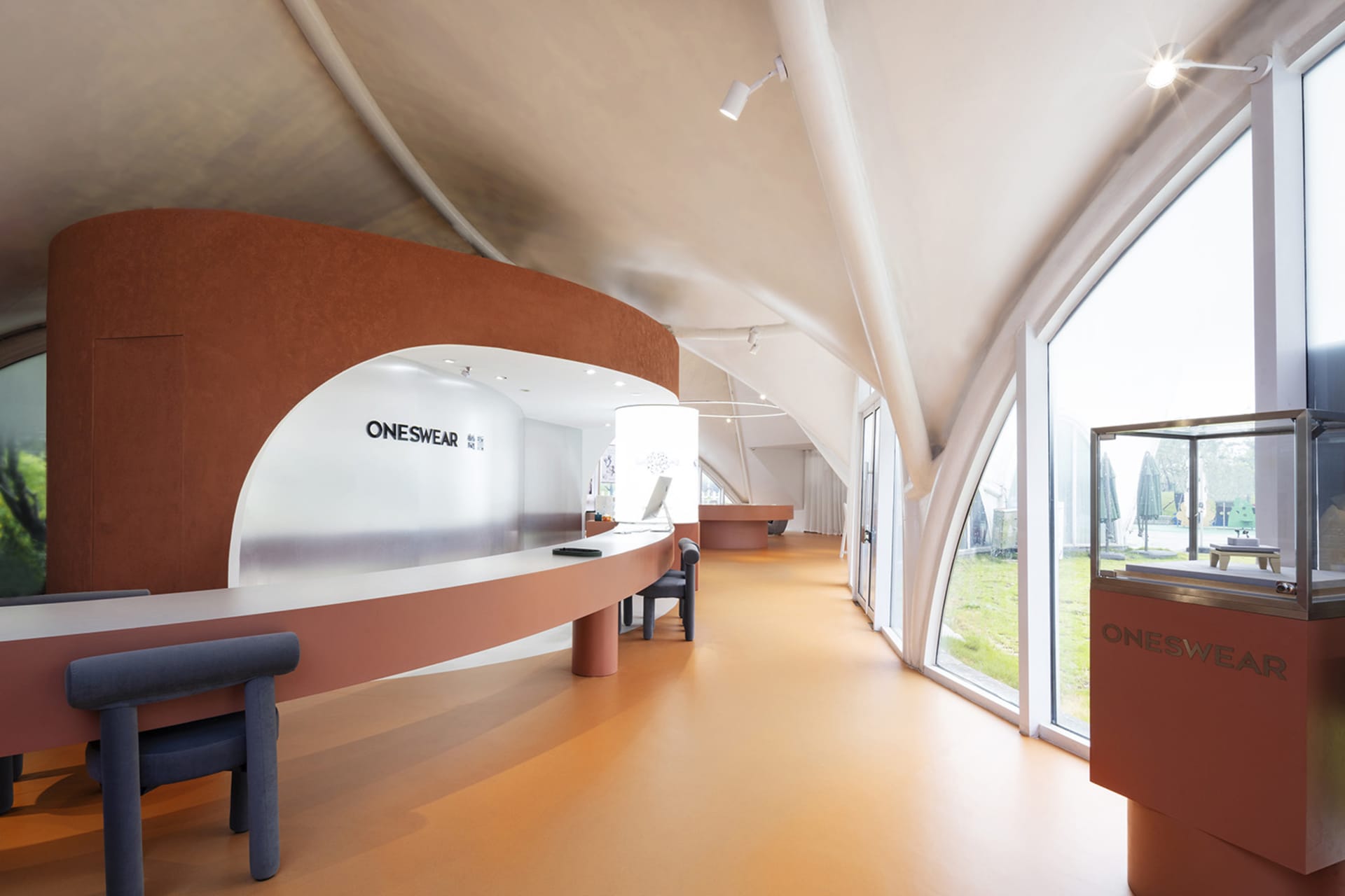 A modern retail showroom featuring curved concrete walls and a spacious interior designed for a contemporary aesthetic.
