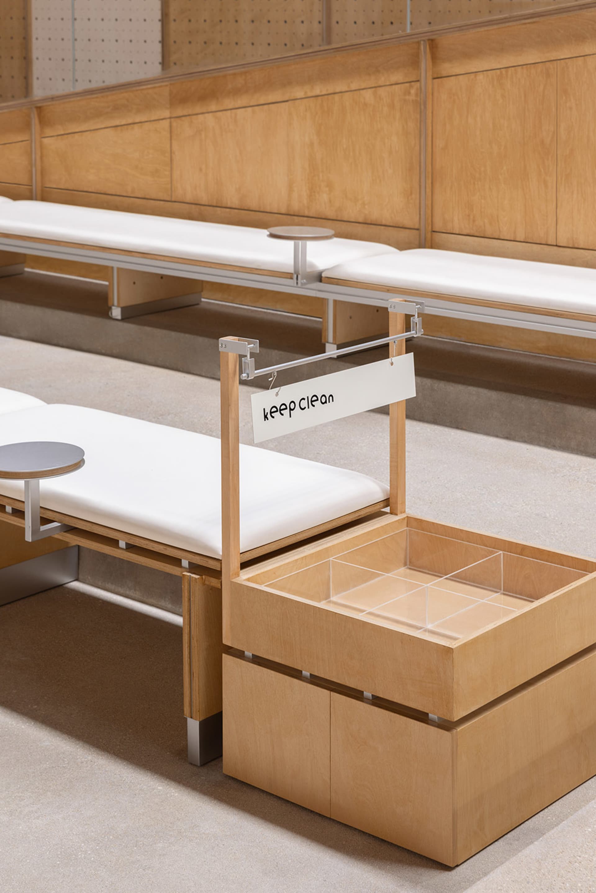 A modern minimalist bench with built-in storage unit made of light wood.