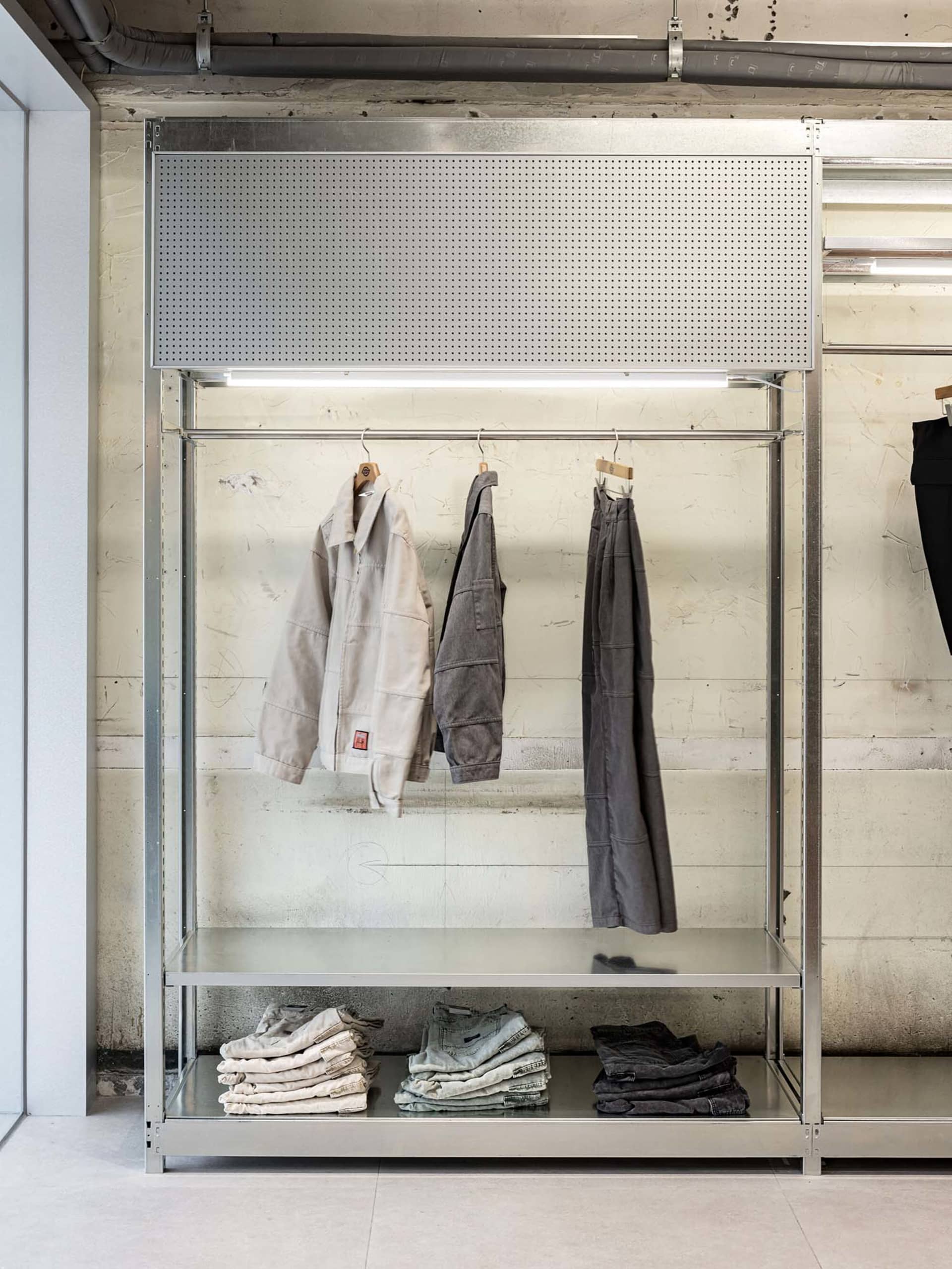 A retail store display featuring clothing items on metal racks with concrete elements.