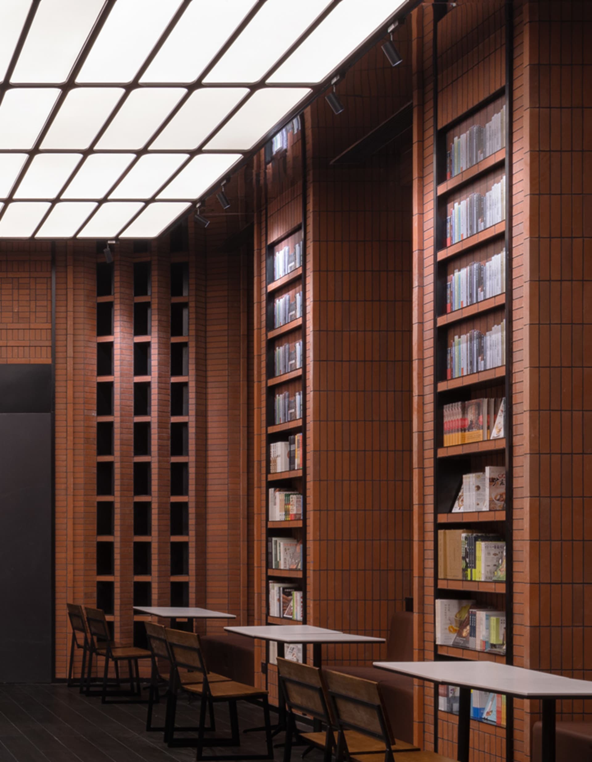 現代圖書館室內,高挑天花板、紅磚牆與木地板。特色為高大書架陳列
