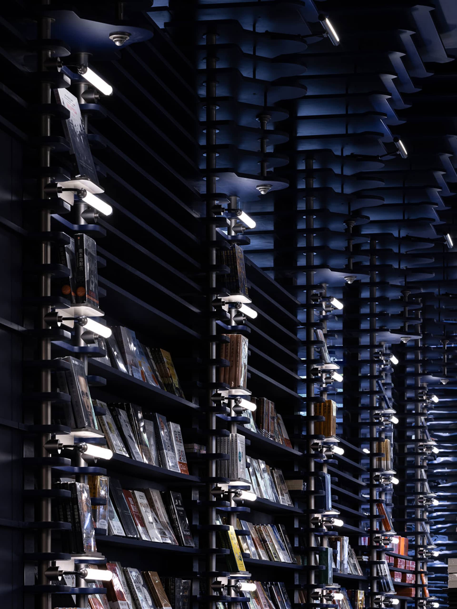 A modern library with metal shelves containing various books and illuminated by evenly spaced lights.