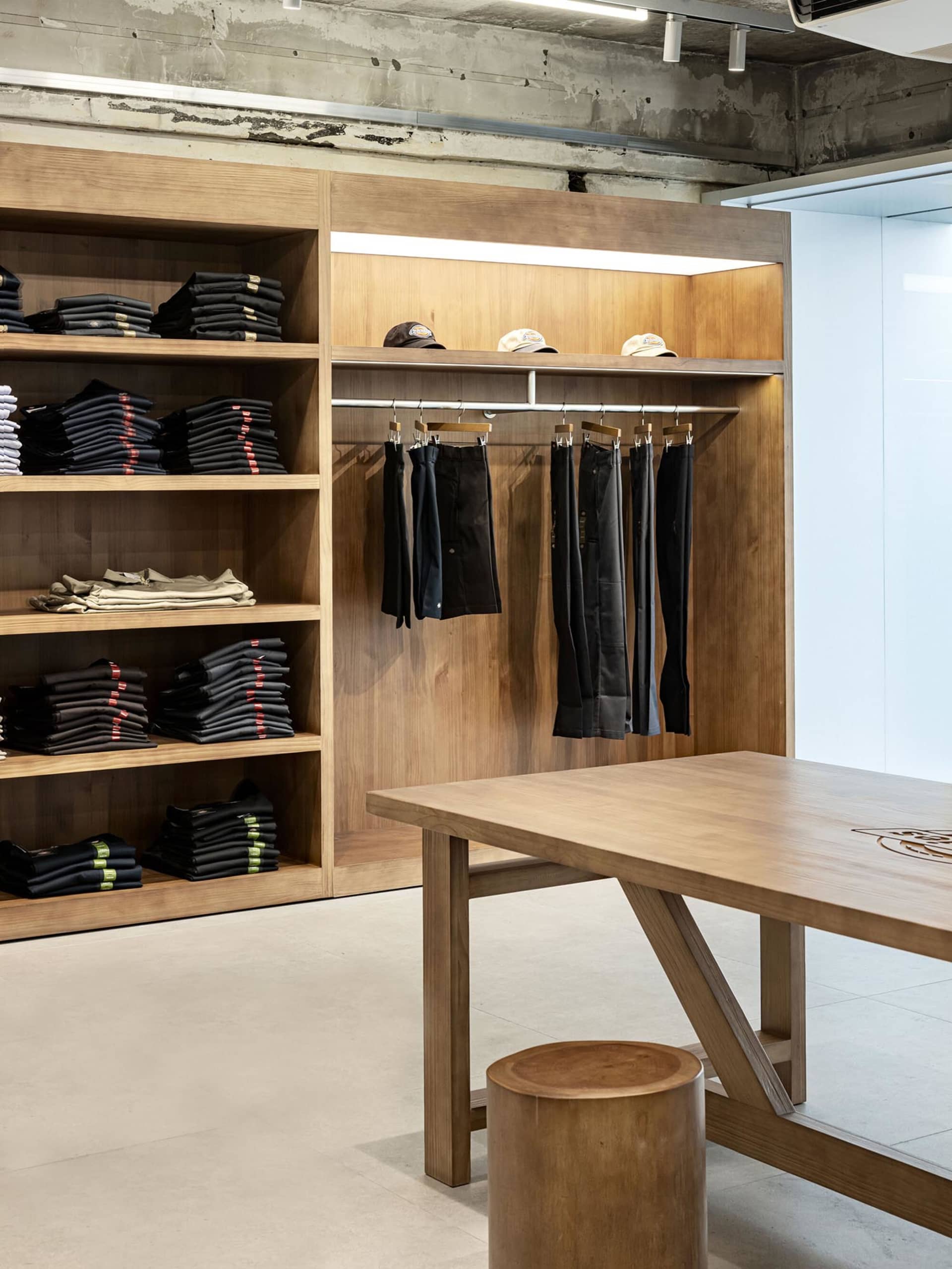 Modern retail store with wooden shelves displaying clothing items.