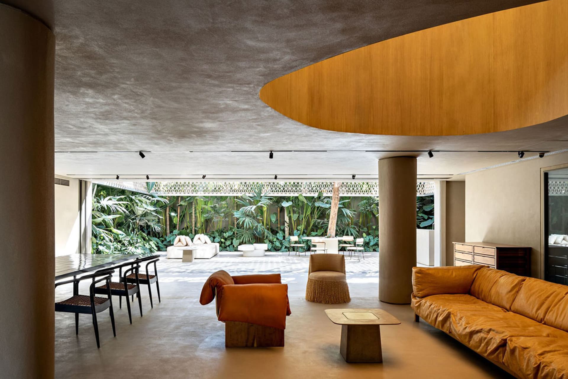 A modern living room featuring concrete floors and walls, with orange and brown furniture.
