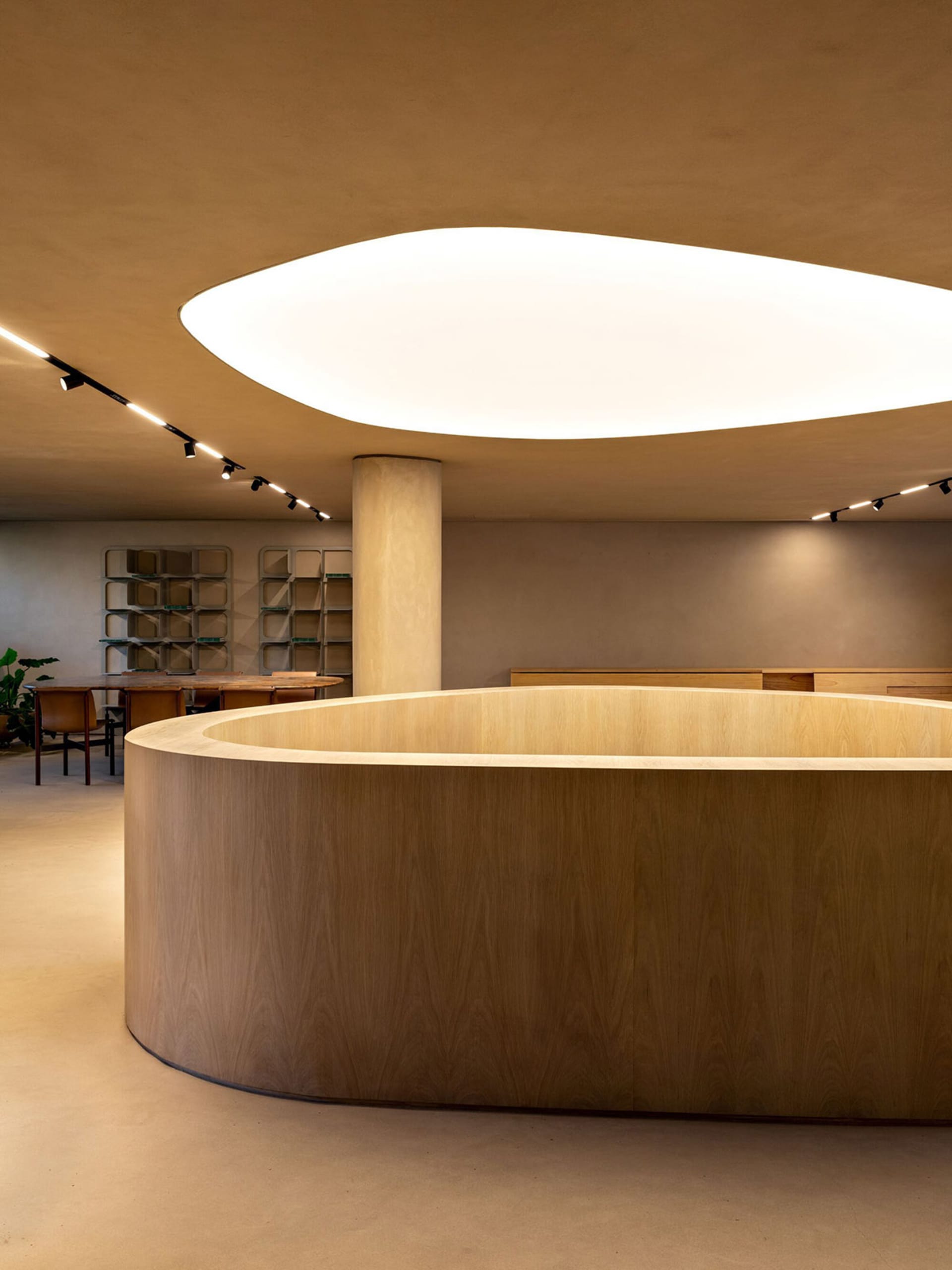 一間現代零售店,設有圓形木質櫃檯與大型橢圓形天花板照明燈具。