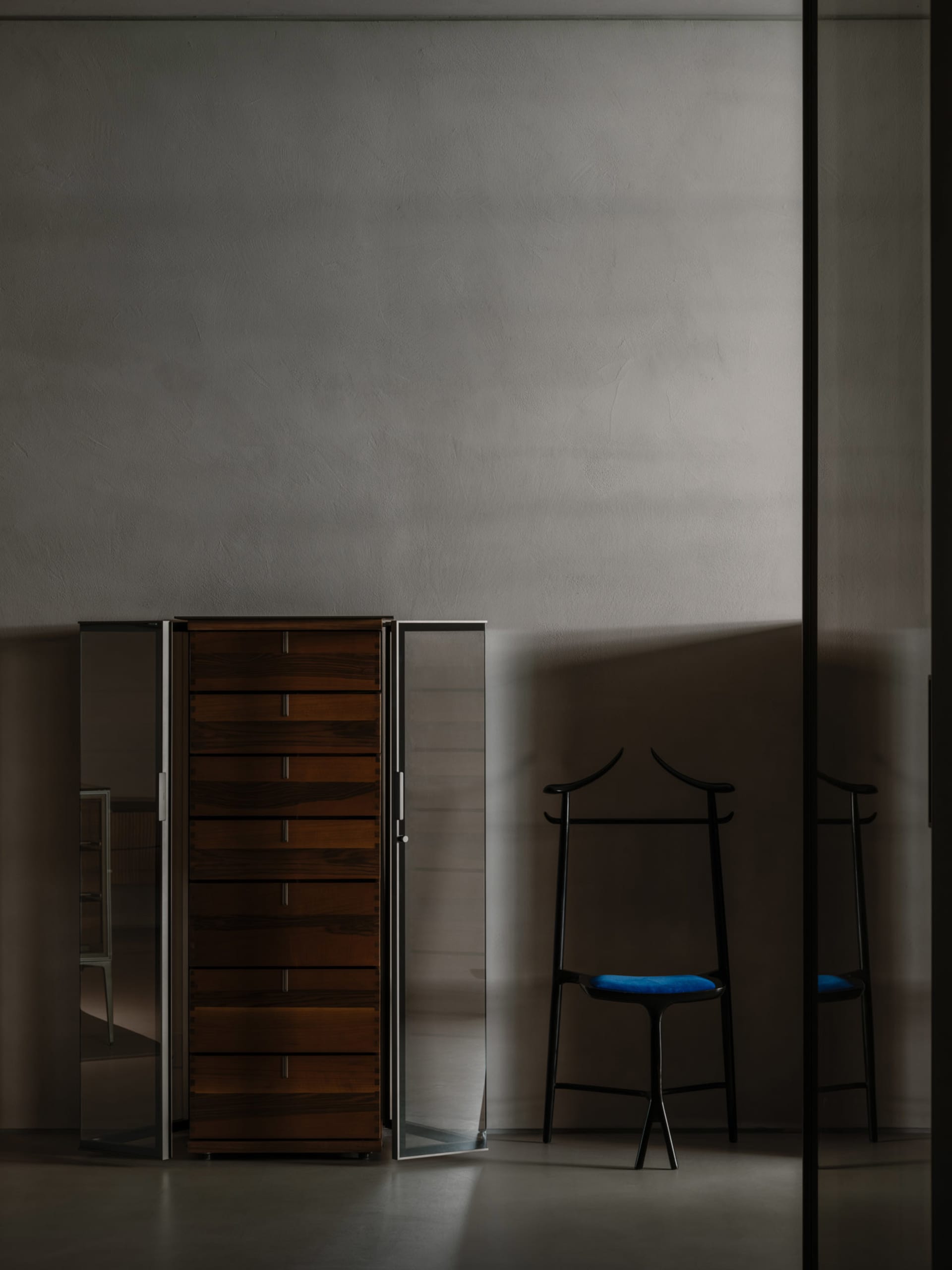 Modern interior design featuring a wooden wardrobe and a black valet stand with blue cushion.
