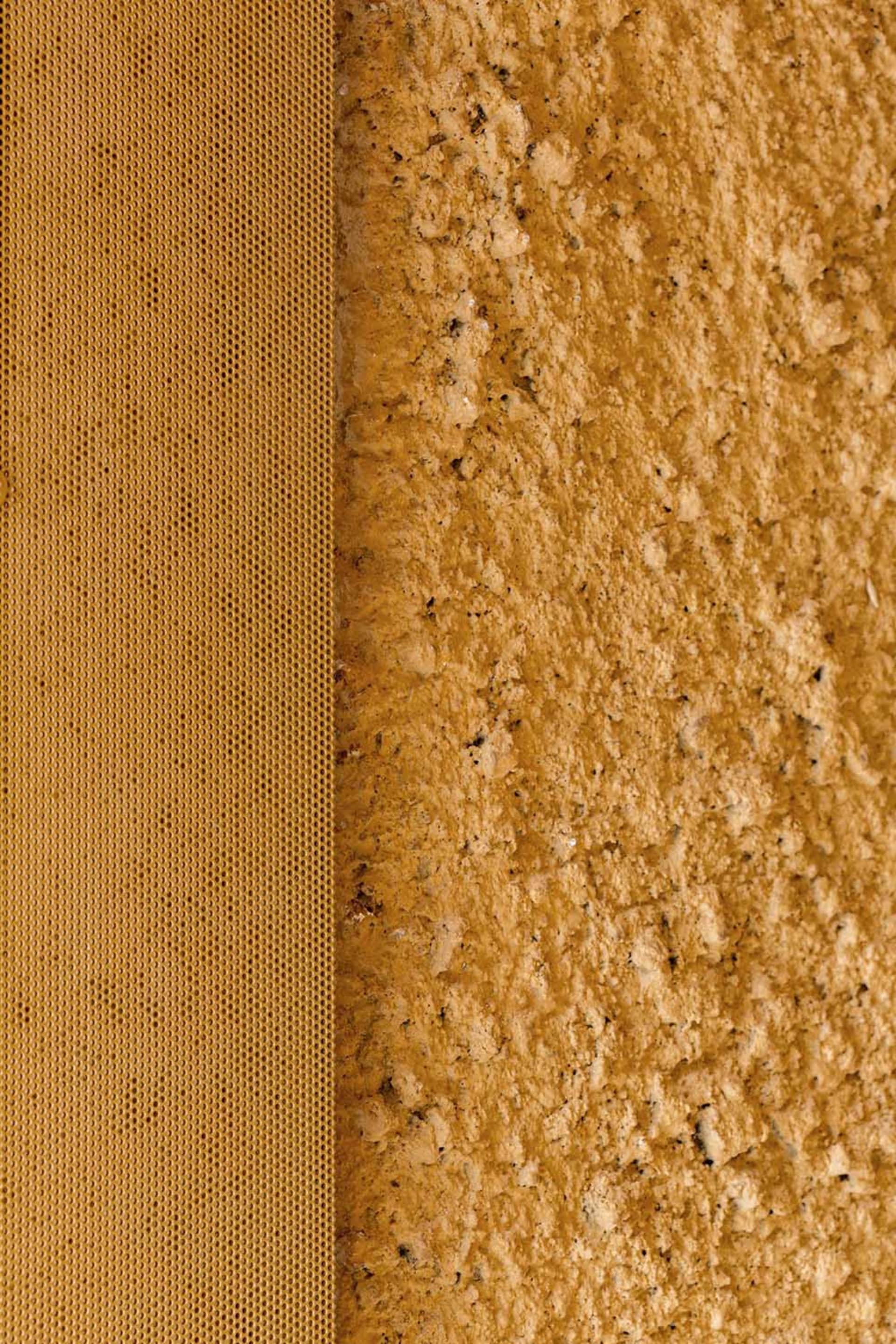 A close-up image showing a textured yellow plaster wall with a honeycomb pattern on the left side.